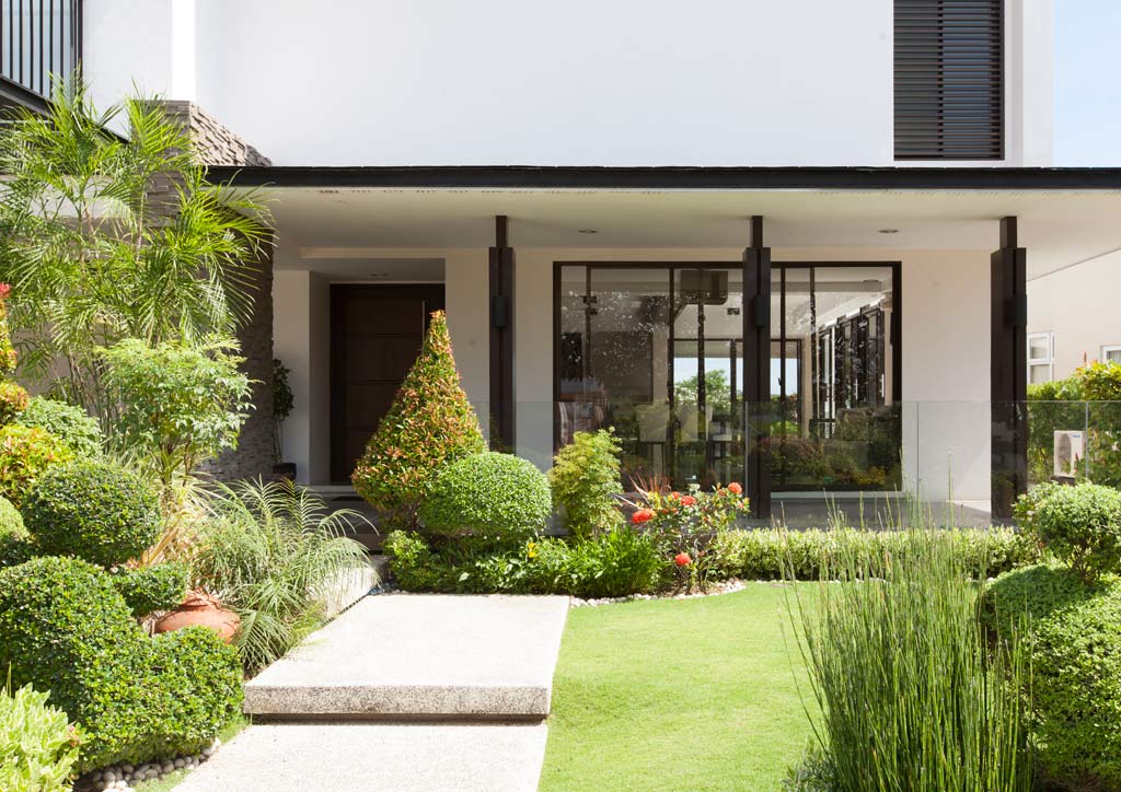 Stone slabs make up the pathway leading to the main entrance. The wraparound patio with roomier areas at the front (facing southeast) and back of the house help protect the ground floor spaces from the sun.