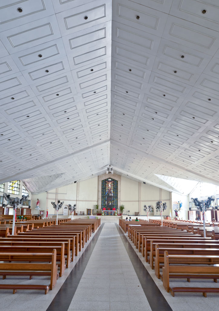 The interior of a Batangas church with a stained glass window and crucifix.
