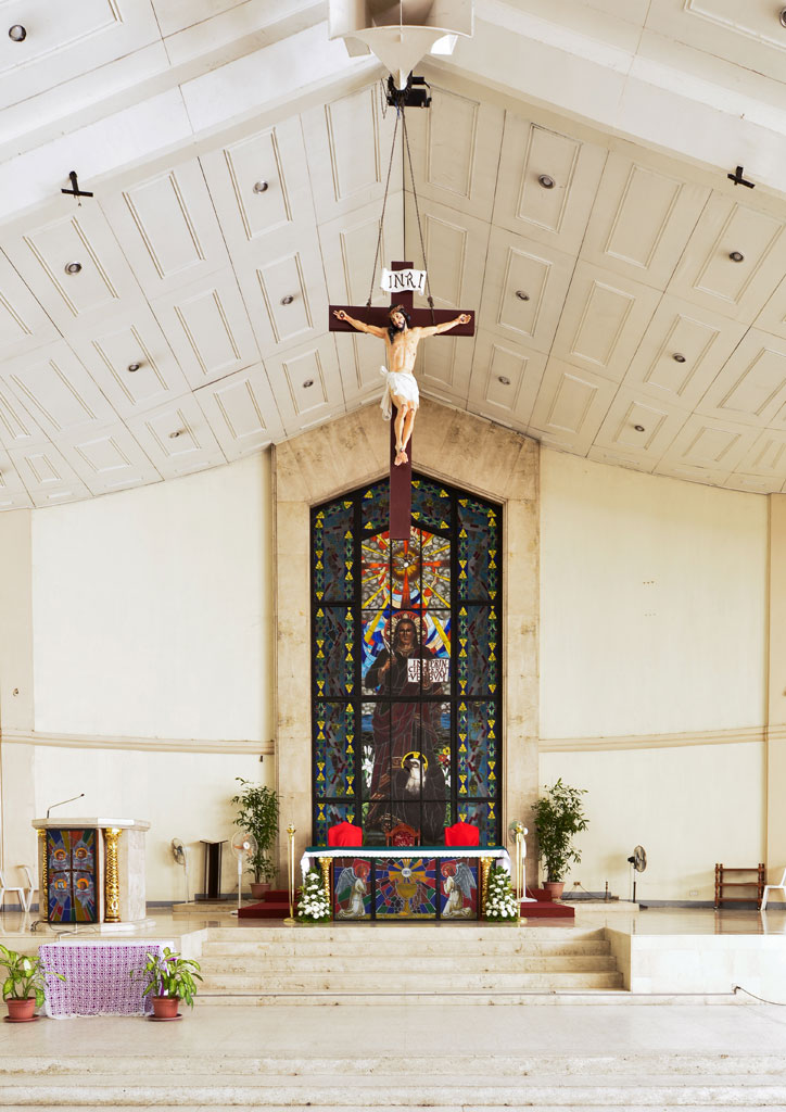 The interior of a Batangas church with a stained glass window and crucifix.
