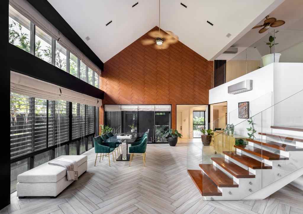 View of living and dining area, featuring floors with herring bone pattern, wood stair treads, and glass bannister