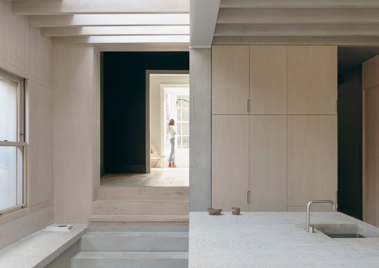 view of the home's entryway from the kitchen with light wooden cabinetry
