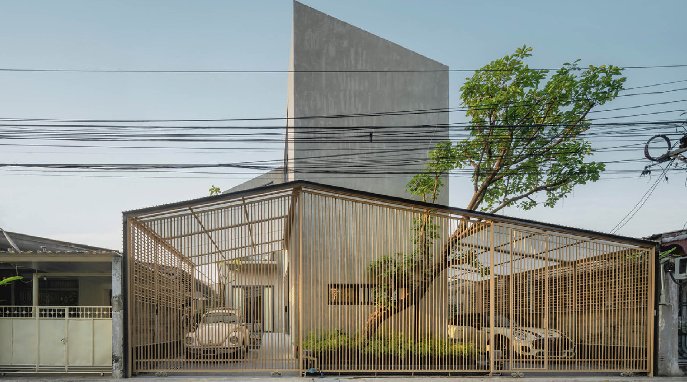 2 storey concrete house in Thailand with a bamboo screen covering the carport.