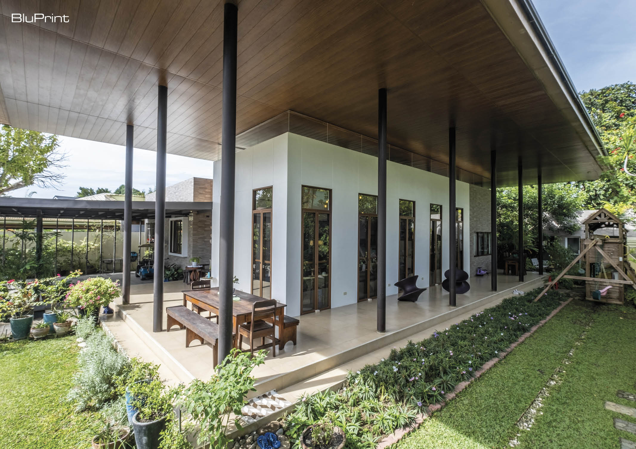 View of a modern home's front yard with outdoor seating areas and green spaces