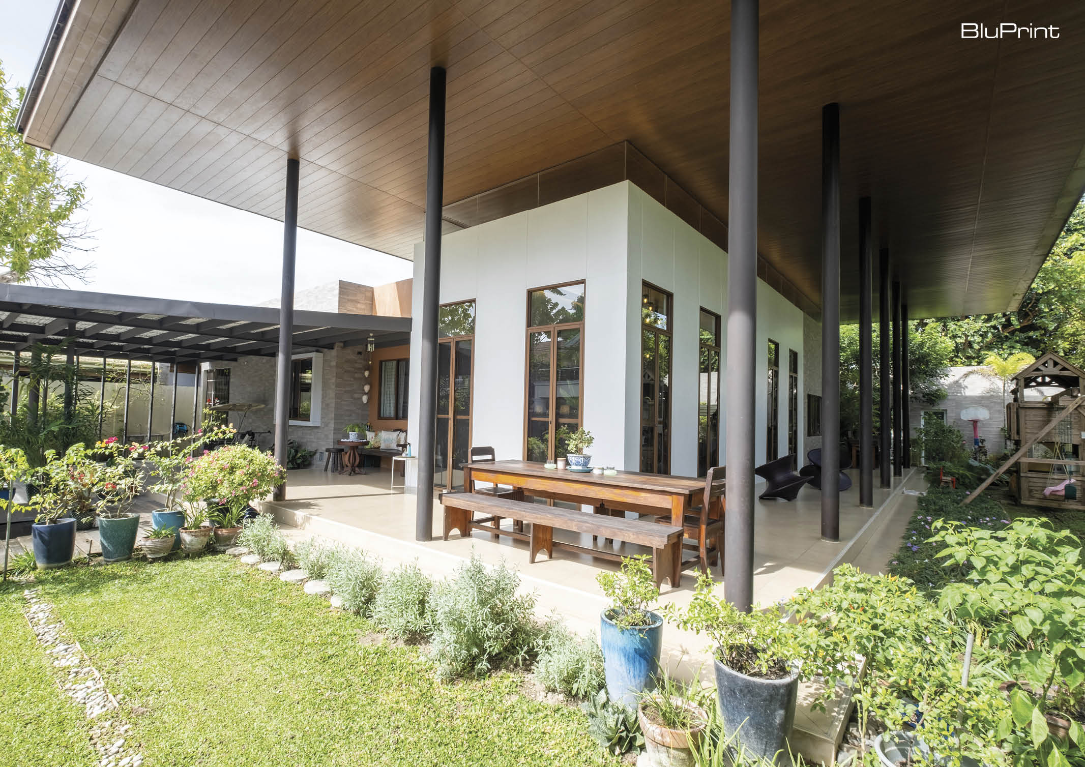 View of a modern home's front yard with outdoor seating areas and green spaces