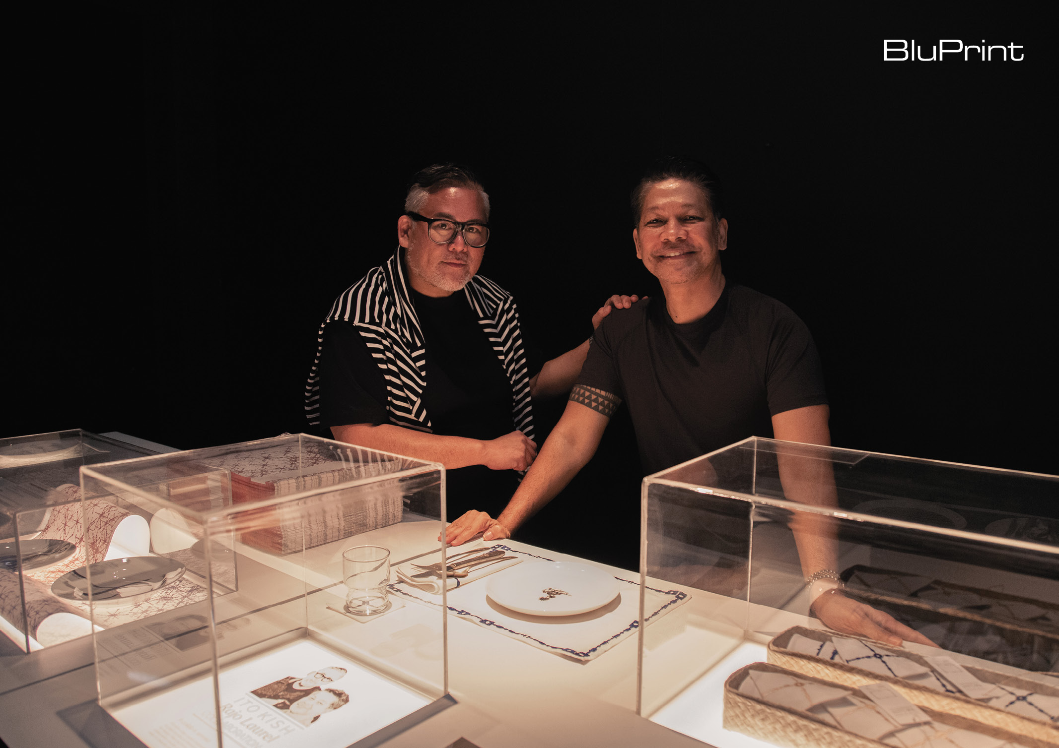 ito kish and rajo laurel standing over their collection of home ware displayed in glass cases