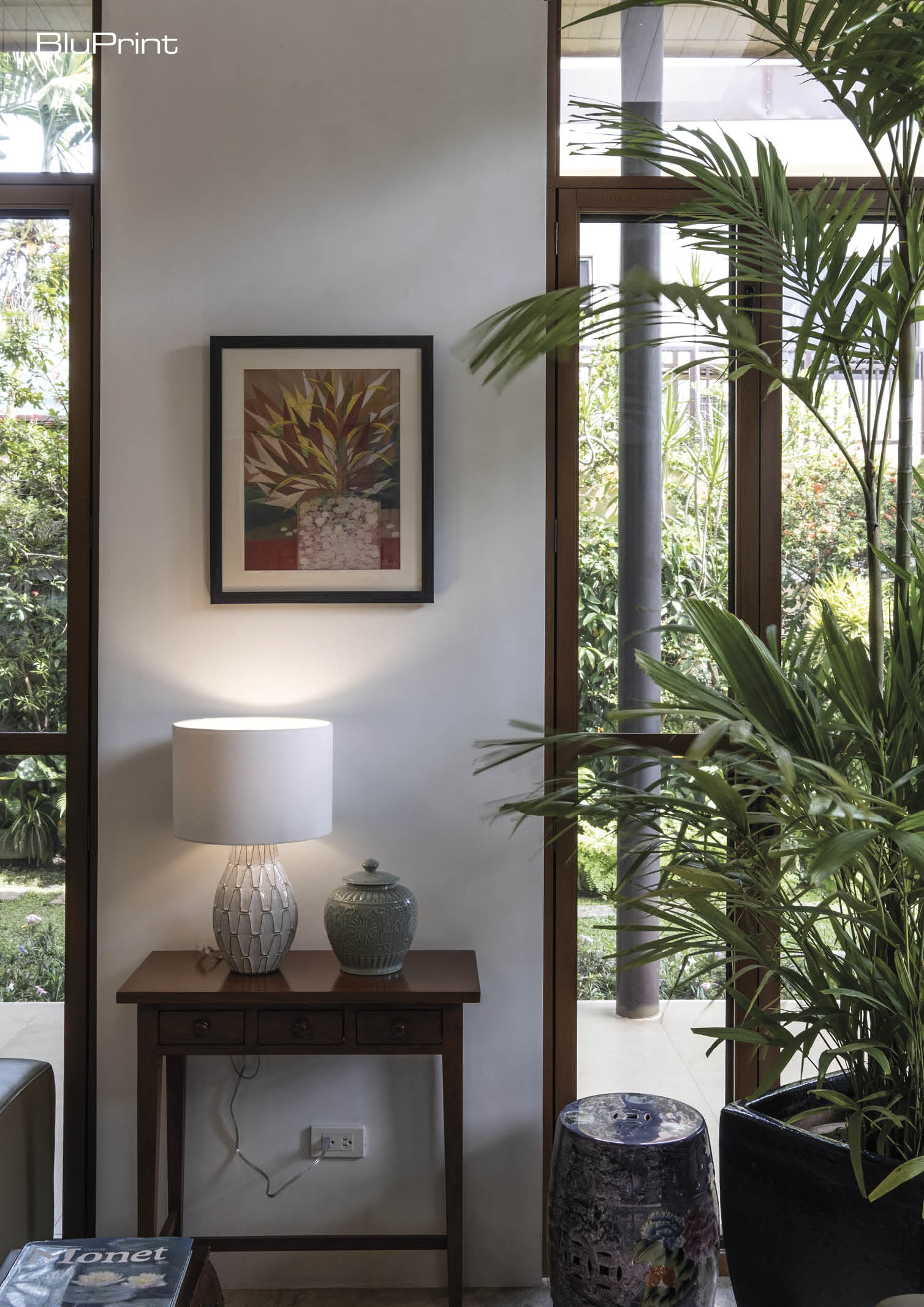 A cozy nook with table lamp and wall art looking out into the outdoor green space