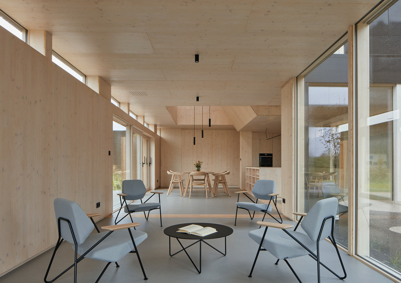 A seating area with grey armchairs inside Warm Nest, a Maggie care facility.