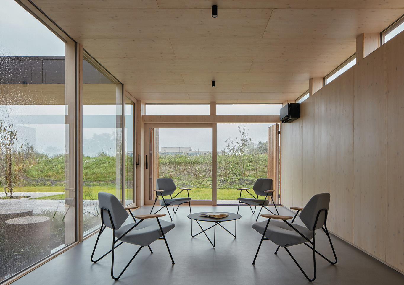 A seating area with grey armchairs inside Warm Nest, a Maggie care facility.