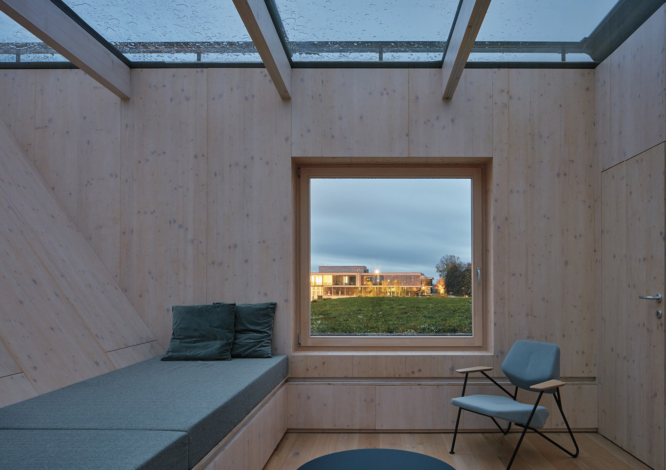 A cozy room with teal day bed and armchair inside Warm Nest, a Maggie care facility.