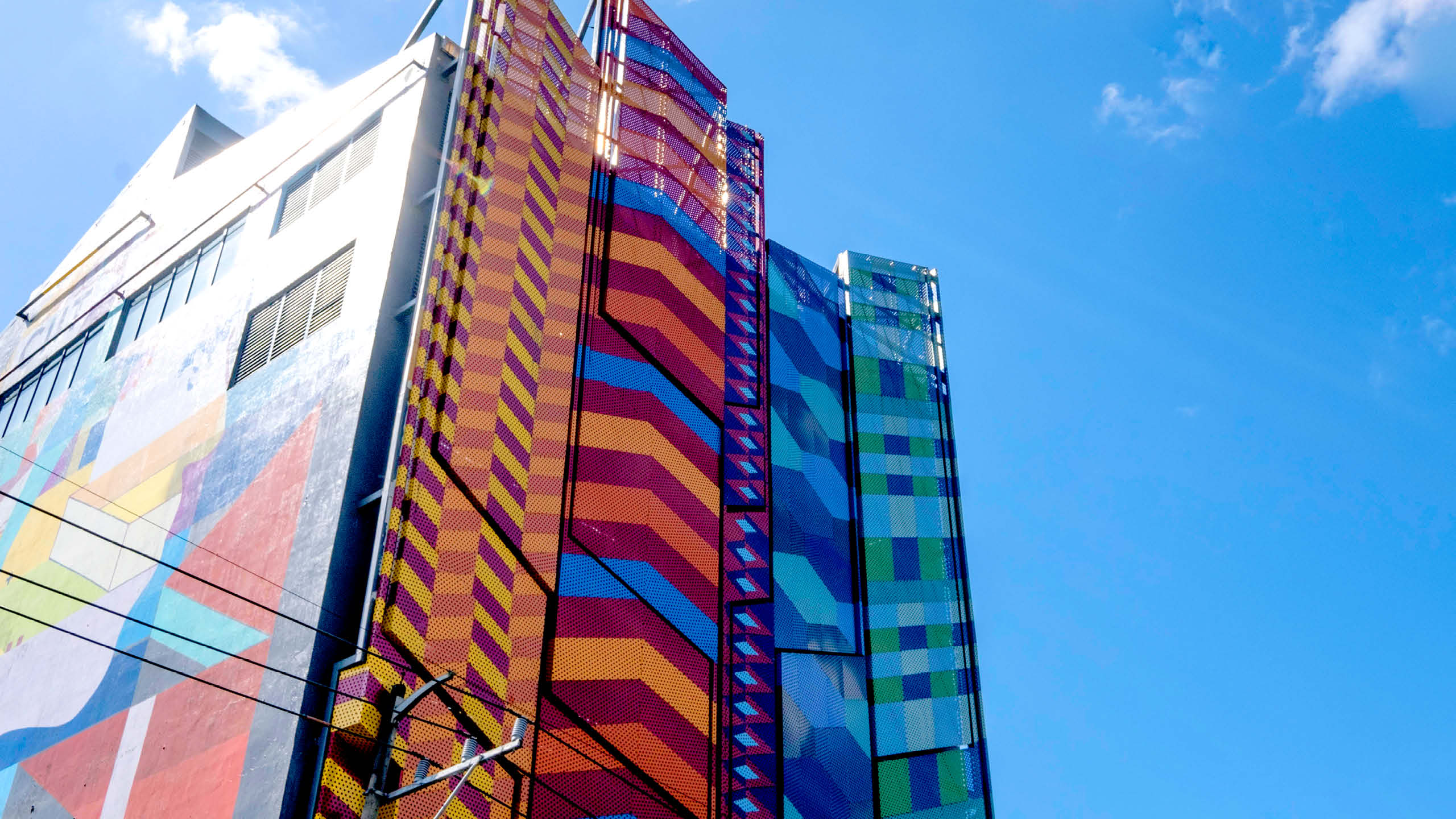 BP 2023 - Feature Cover photo2 - BluPrint Street View of a building's colorful facade in blue, orange, green, and red geometric patterns.