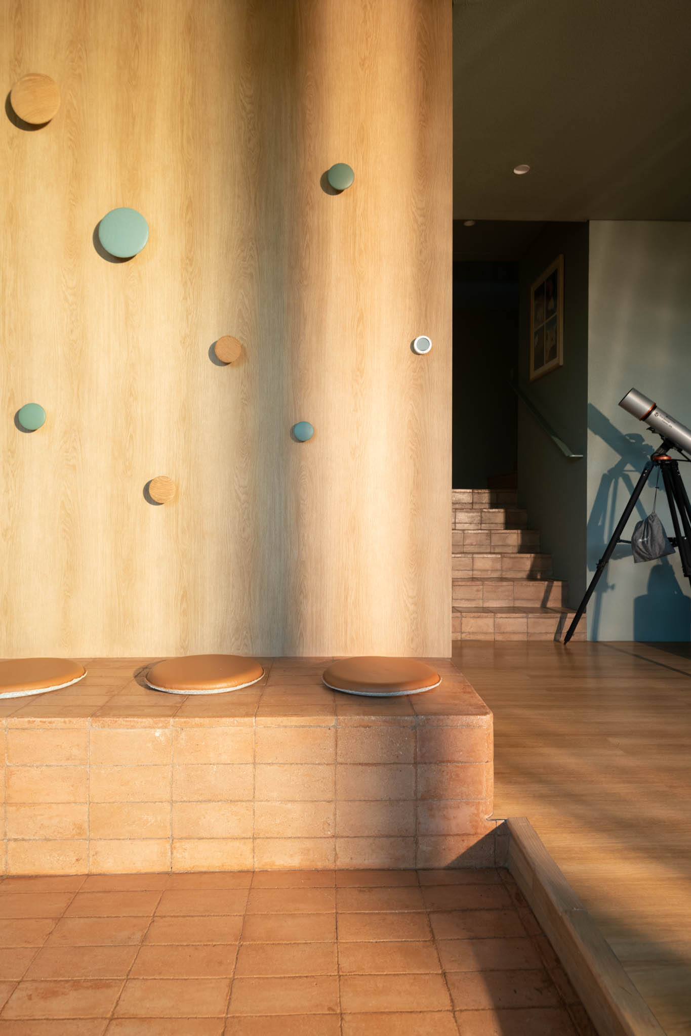 R House's foyer with round wooden pegs for hanging clothes and a brick bench for changing shoes.