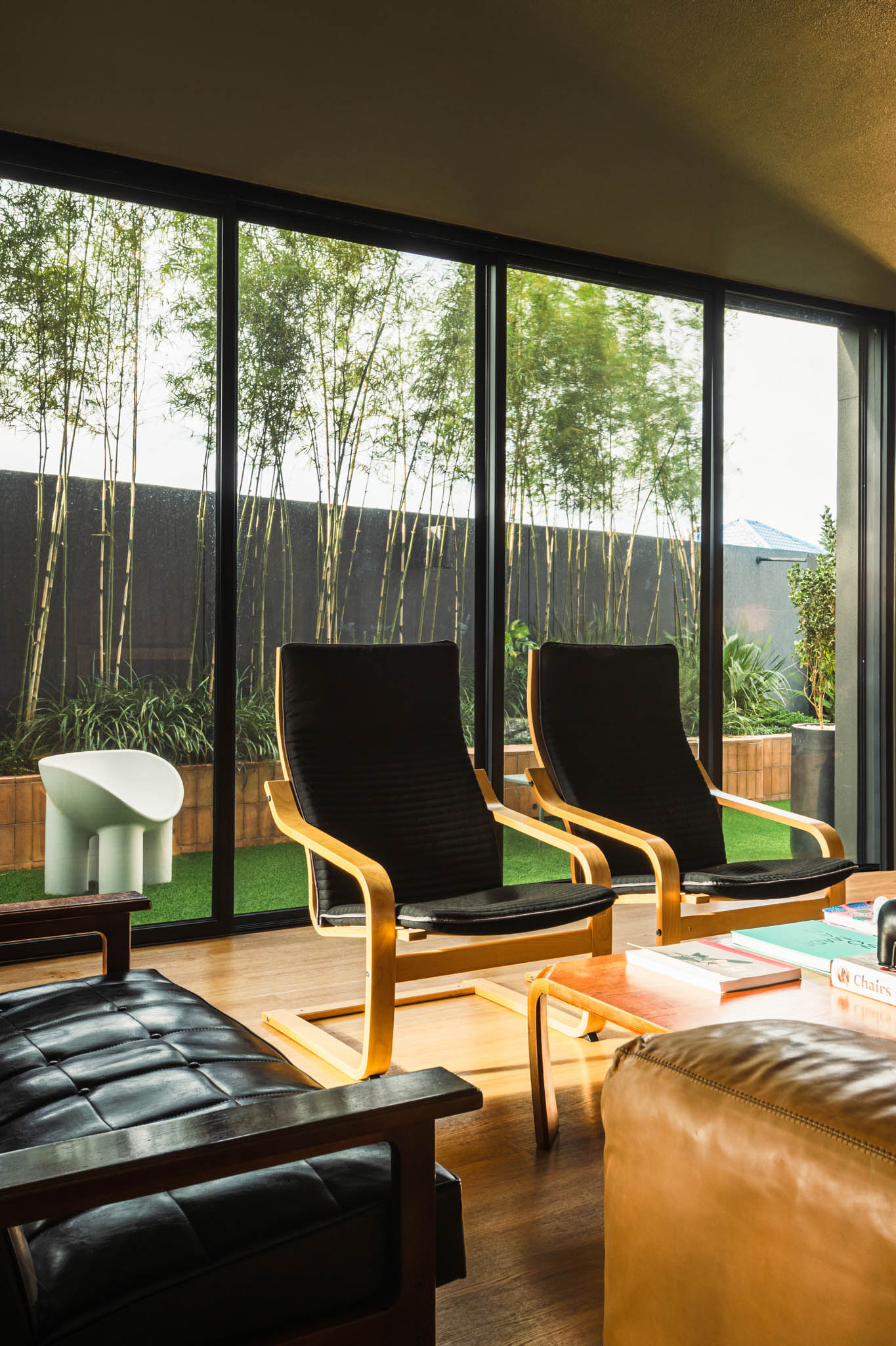 The living room featuring two mid century modern arm chairs against floor to ceiling windows.