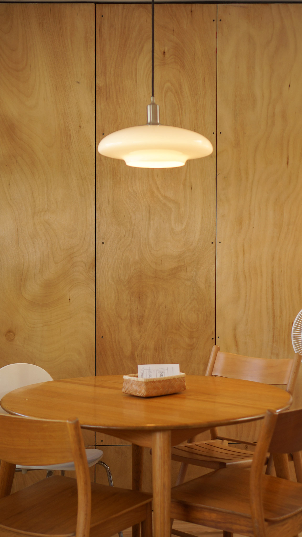 A close up a round dining table next wooden panels and modern pendant lamp. A small house design in San Juan, La Union.