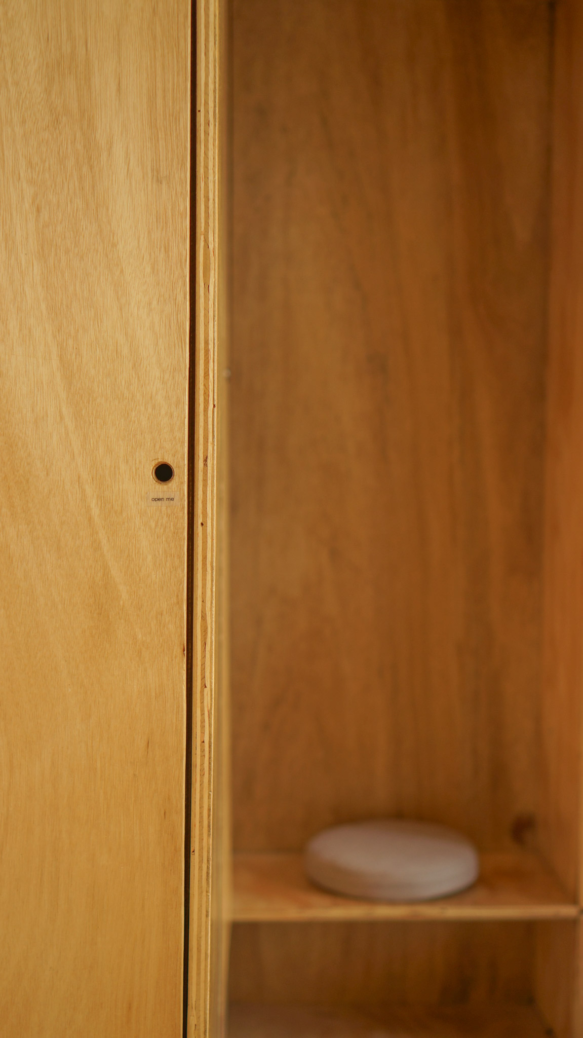 A small bench with a round cushion within a plywood built-in inside a  small house design.