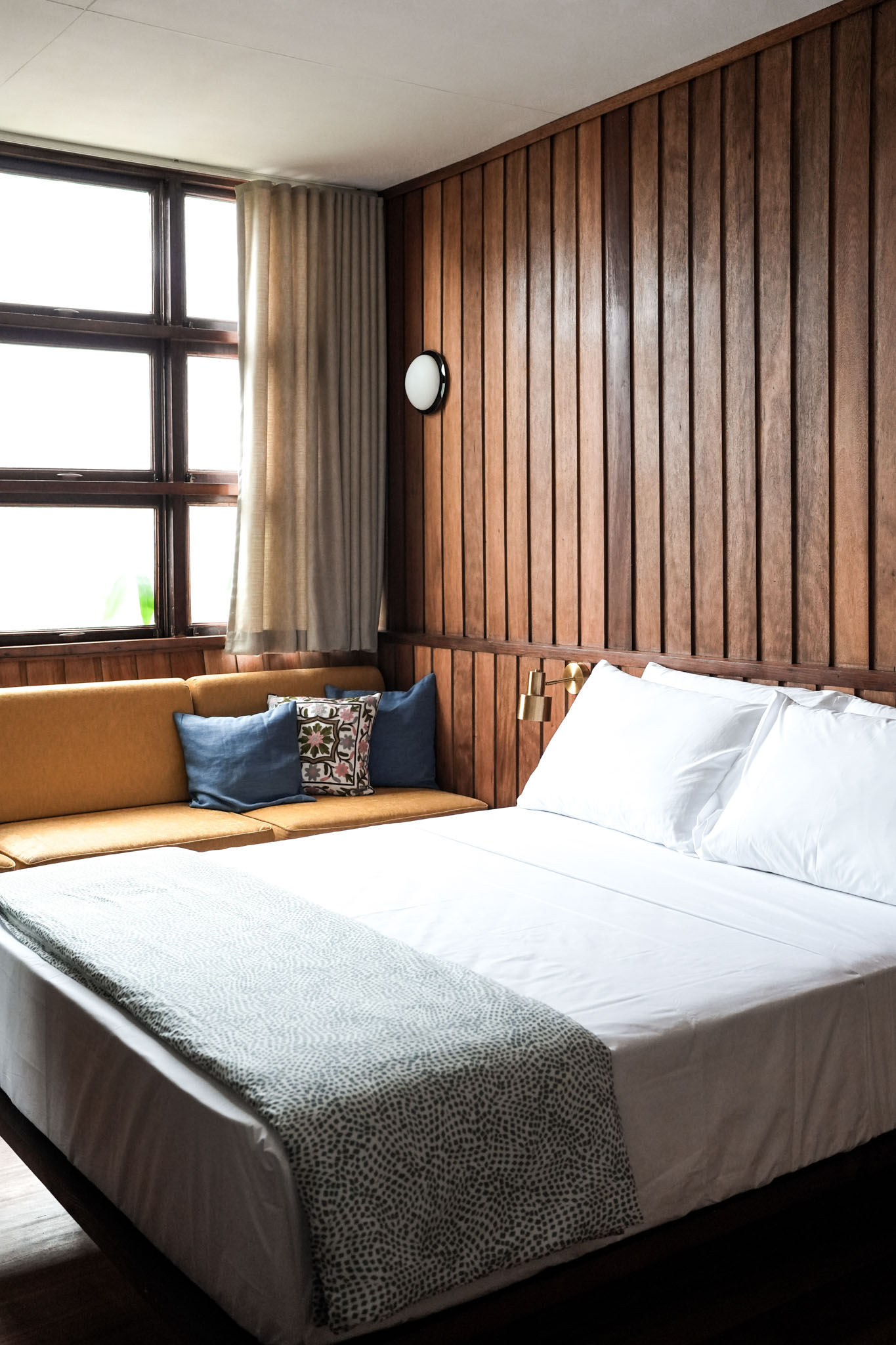 A bedroom in the Lark located in San Juan, La Union, with a small brown window seat and reclaimed wood wall panels.