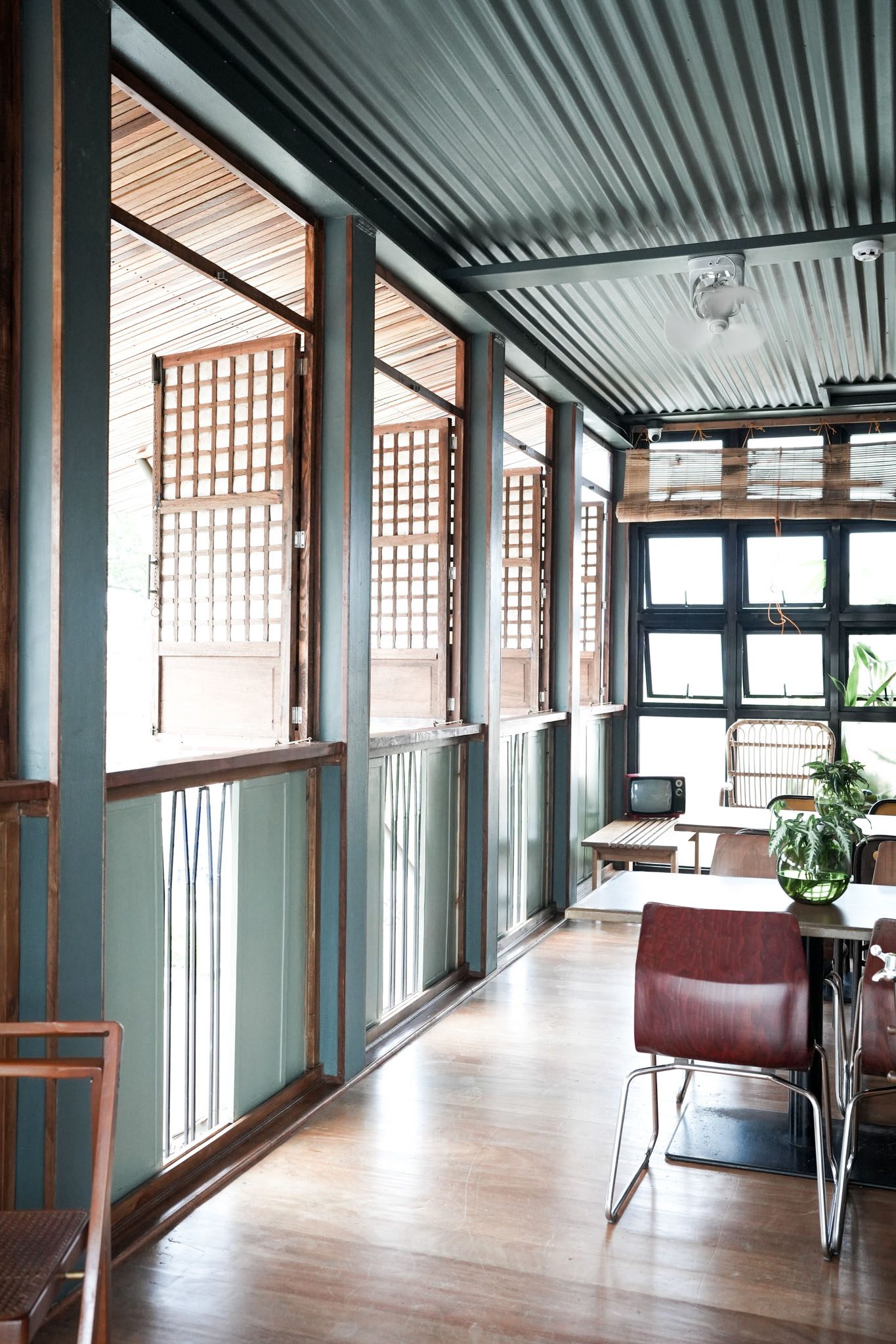 An open air lanai area of the Lark in San Juan La Union, with seating and wide open windows with capiz shutters.