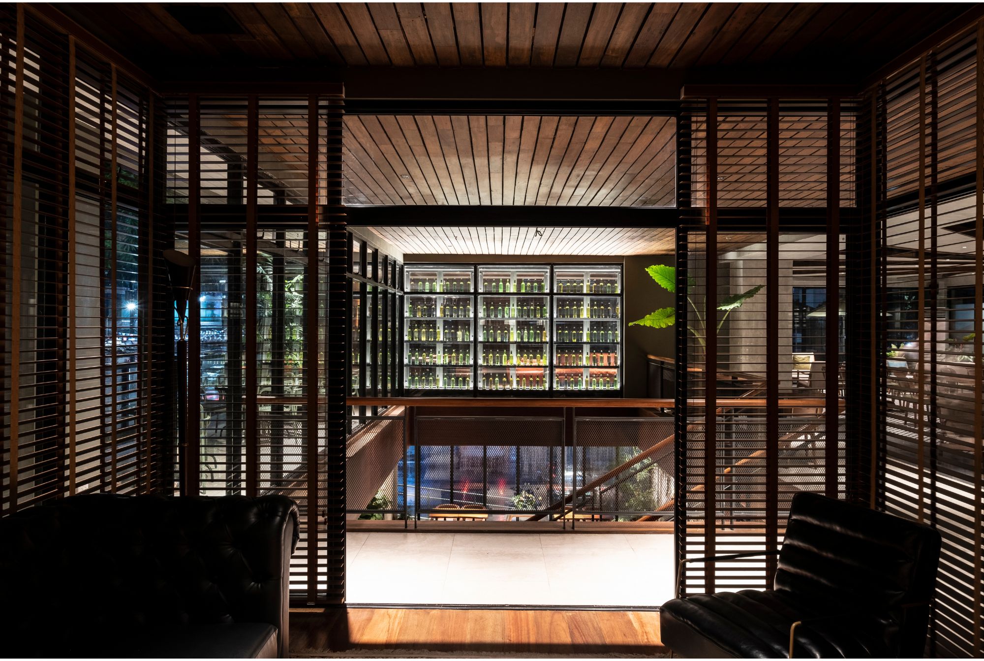 A view from a cigar room toward the wine cellar with bottles on display in a glass case.