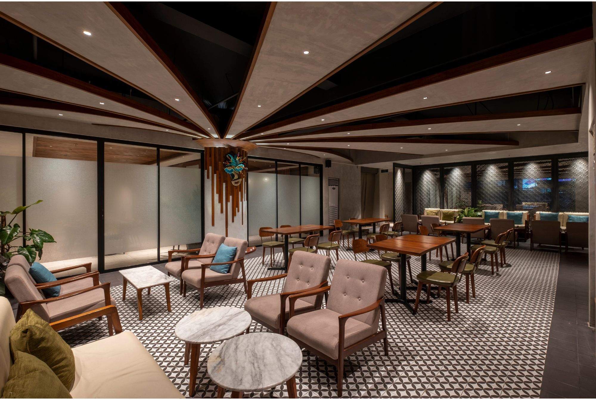 A dining area with tables, seating, and a lounge area with an architectural ceiling treatement.