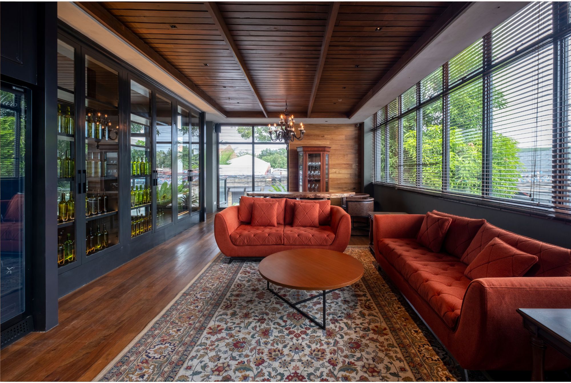 Cafe Bobs wine cellar with terracota colored seating, ornate rug, and large glass display case filled with wine bottles.