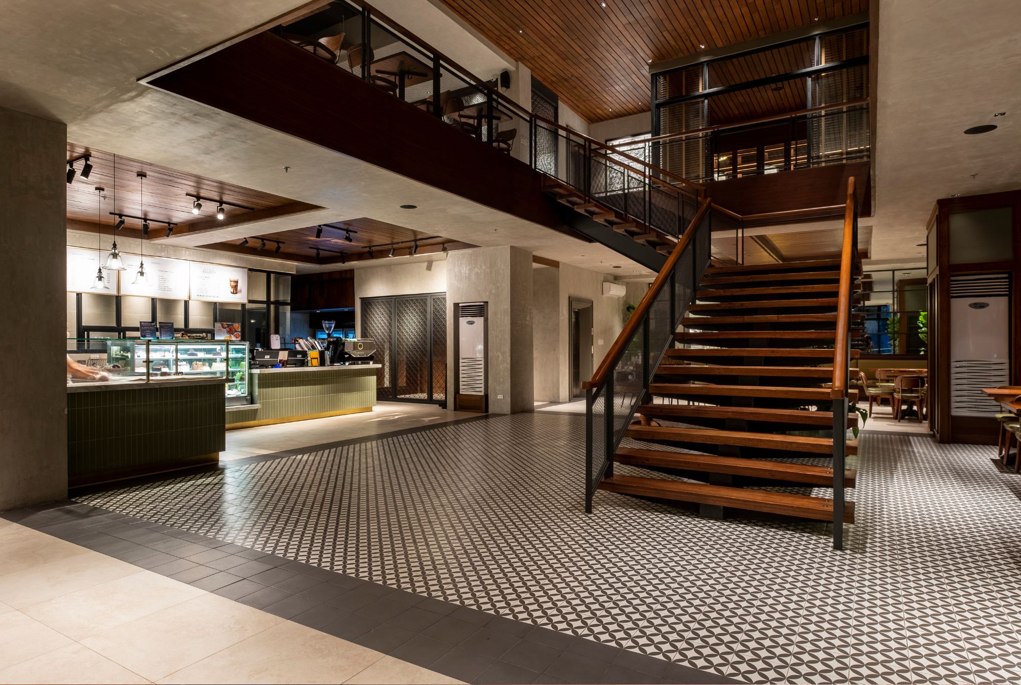 The central staircase in a wide open space at Cafe Bobs designed by Larawan Ink, with wooden treads and metal balustrade.