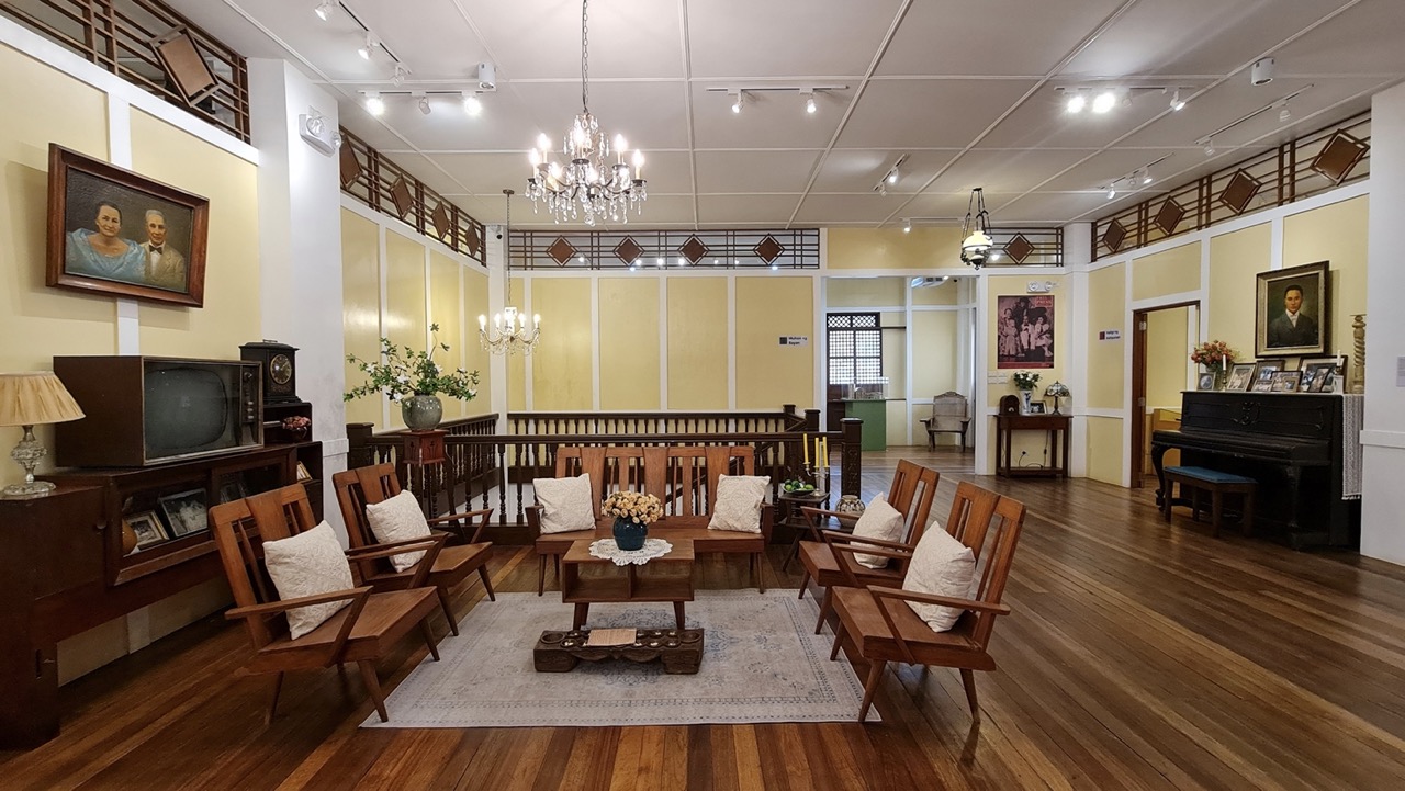 The living room of Dr. Pio Valenzuela's bahay na bato, now a museum, with traditional wooden furniture, light yellow walls, and hard wood floors.