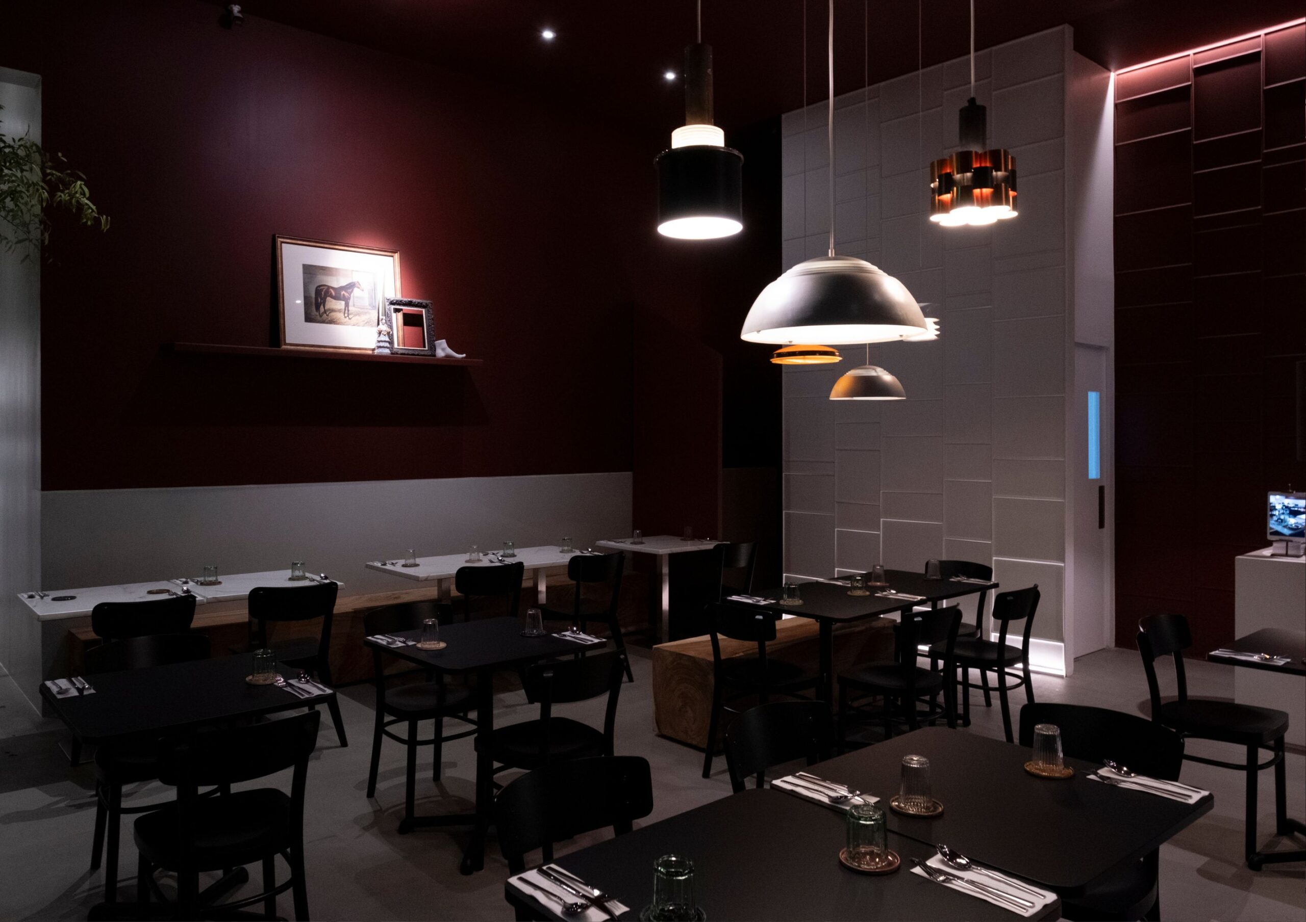 The minimalist dining area of Ito Kish Design Food with burgundy walls and vintage light fixtures.