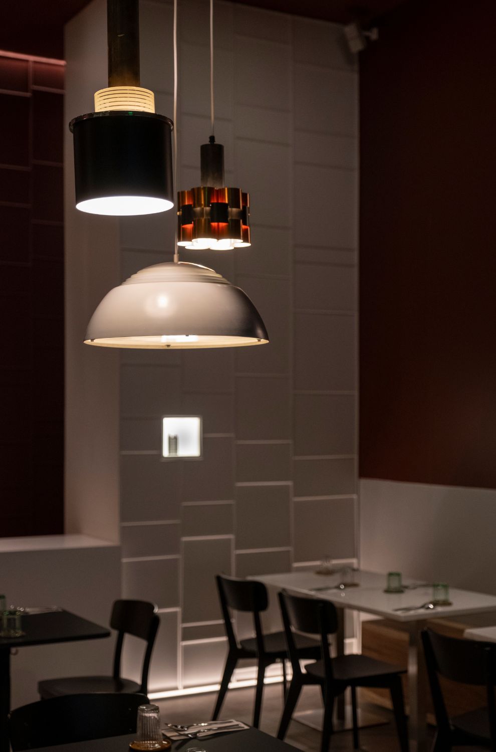 The minimalist dining area of Ito Kish Design Food with burgundy walls and vintage light fixtures.