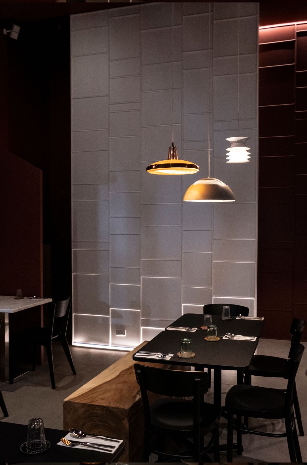 The minimalist dining area of Ito Kish Design Food with burgundy walls and vintage light fixtures.