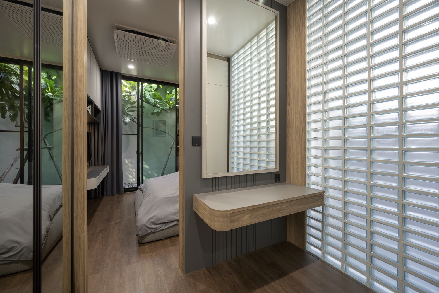 Bedroom with a view of tree and a glass wall.