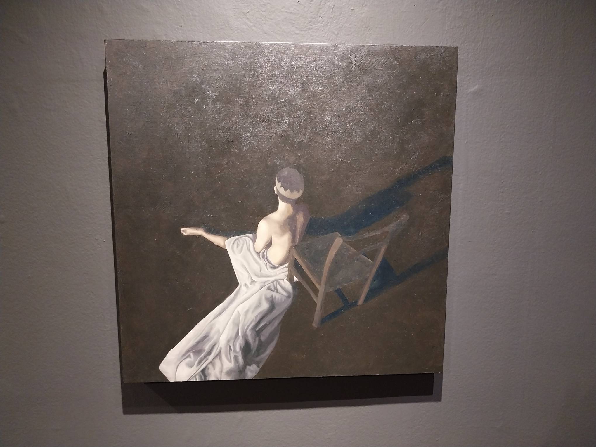 Painting of a person sitting on the floor next to a chair. Photo by Elle Yap.