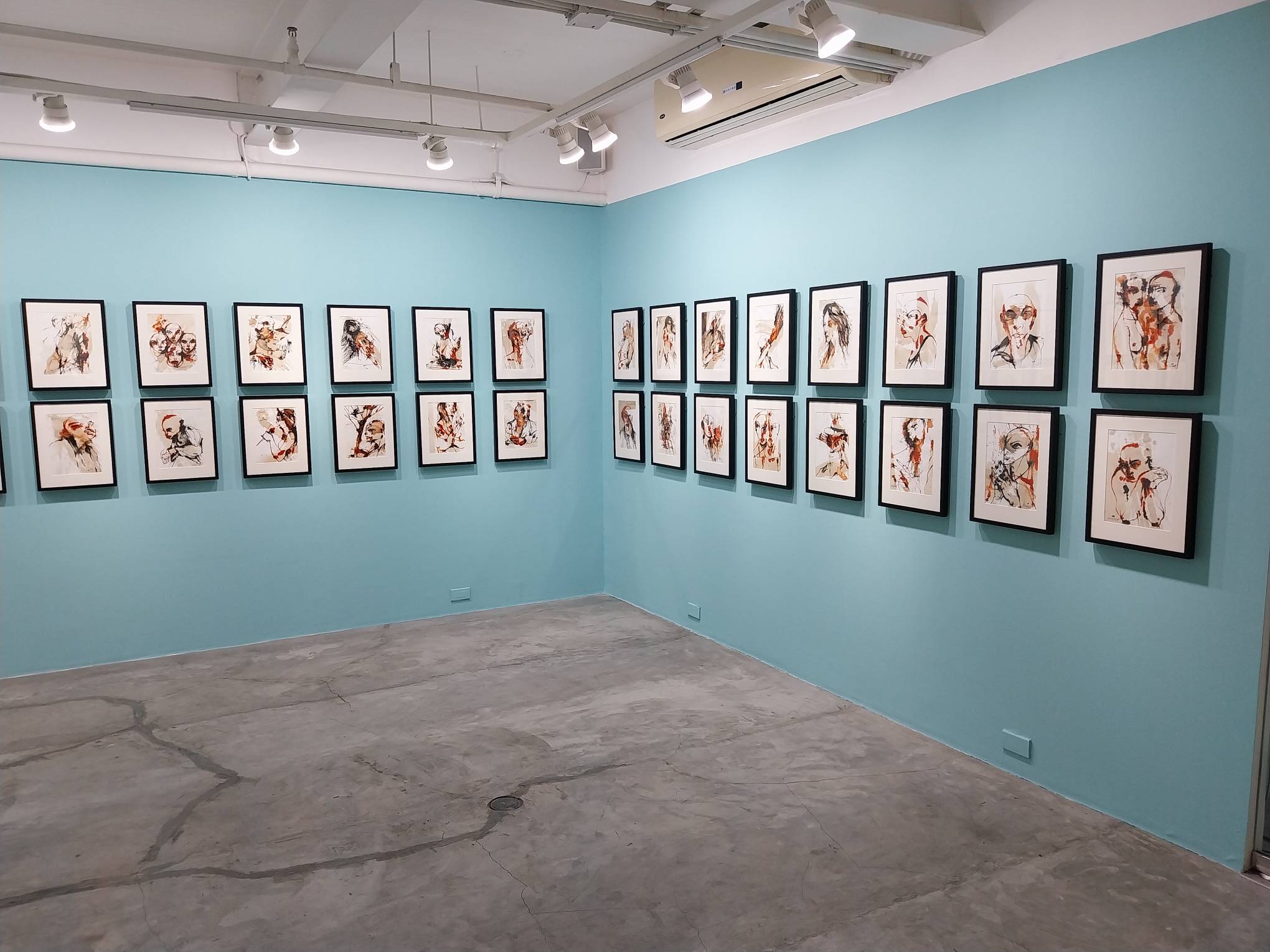 Two sides of the exhibit filled with paintings. Photo by Elle Yap.