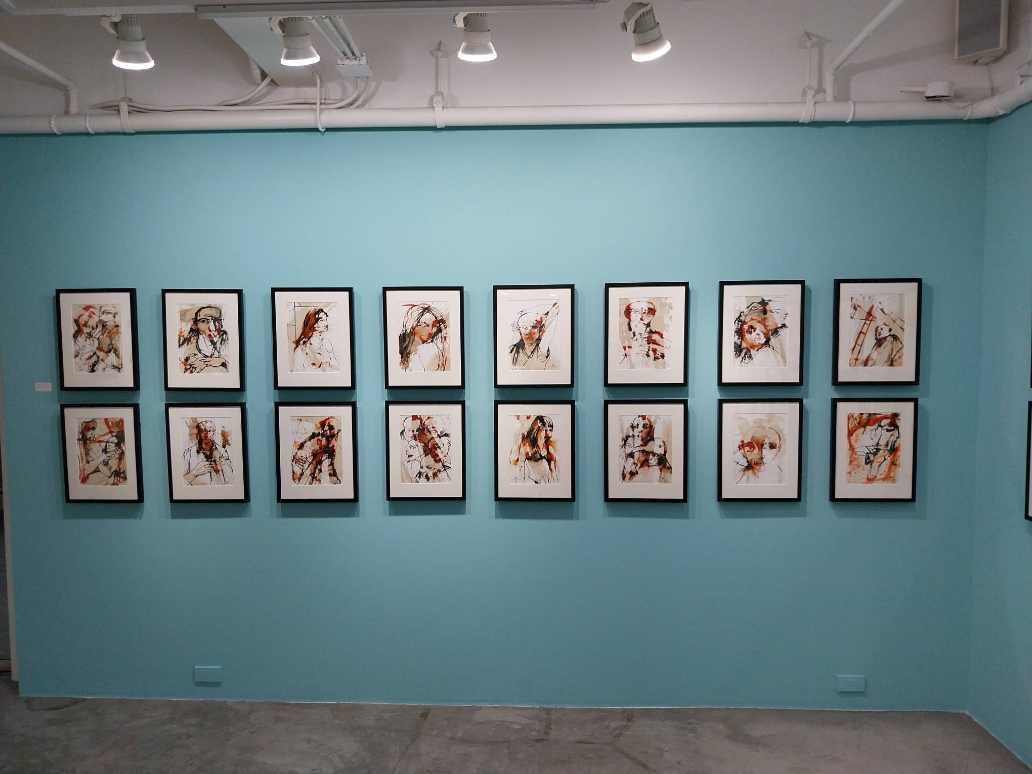 Blue wall with multiple paintings. Photo by Elle Yap.