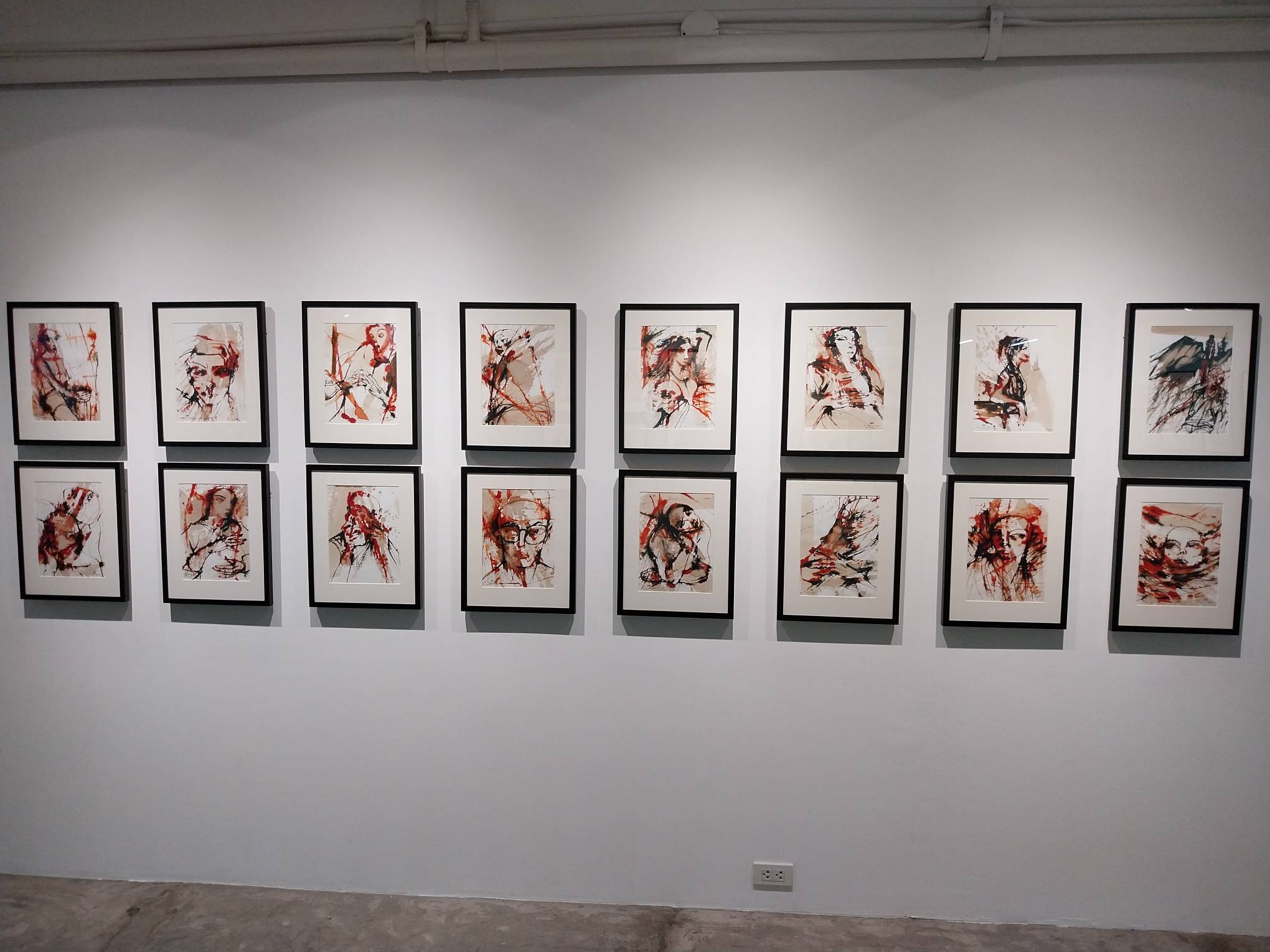 A white wall with multiple paintings. Photo by Elle Yap.