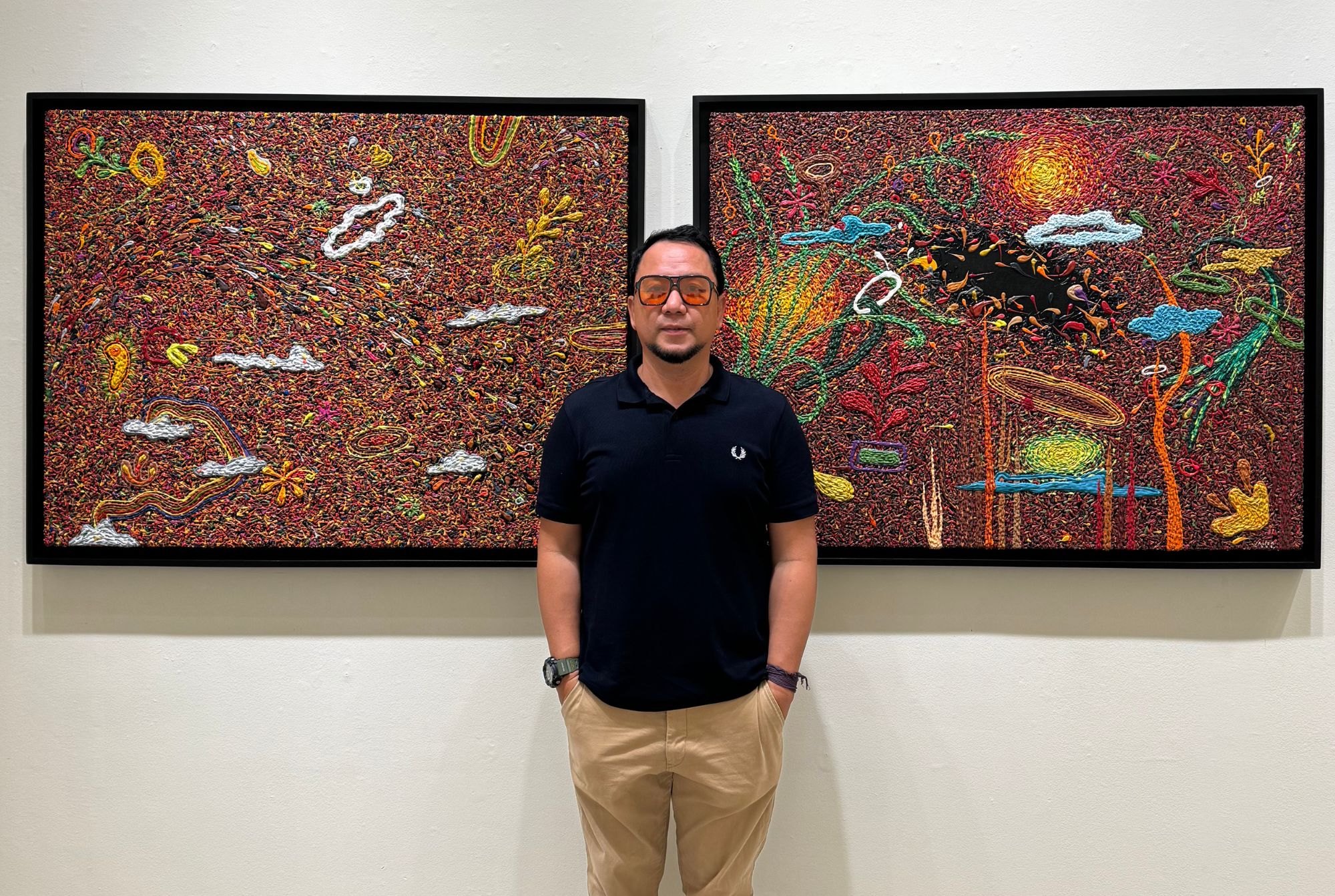Artist Binong Javier in front of two of his paintings for 