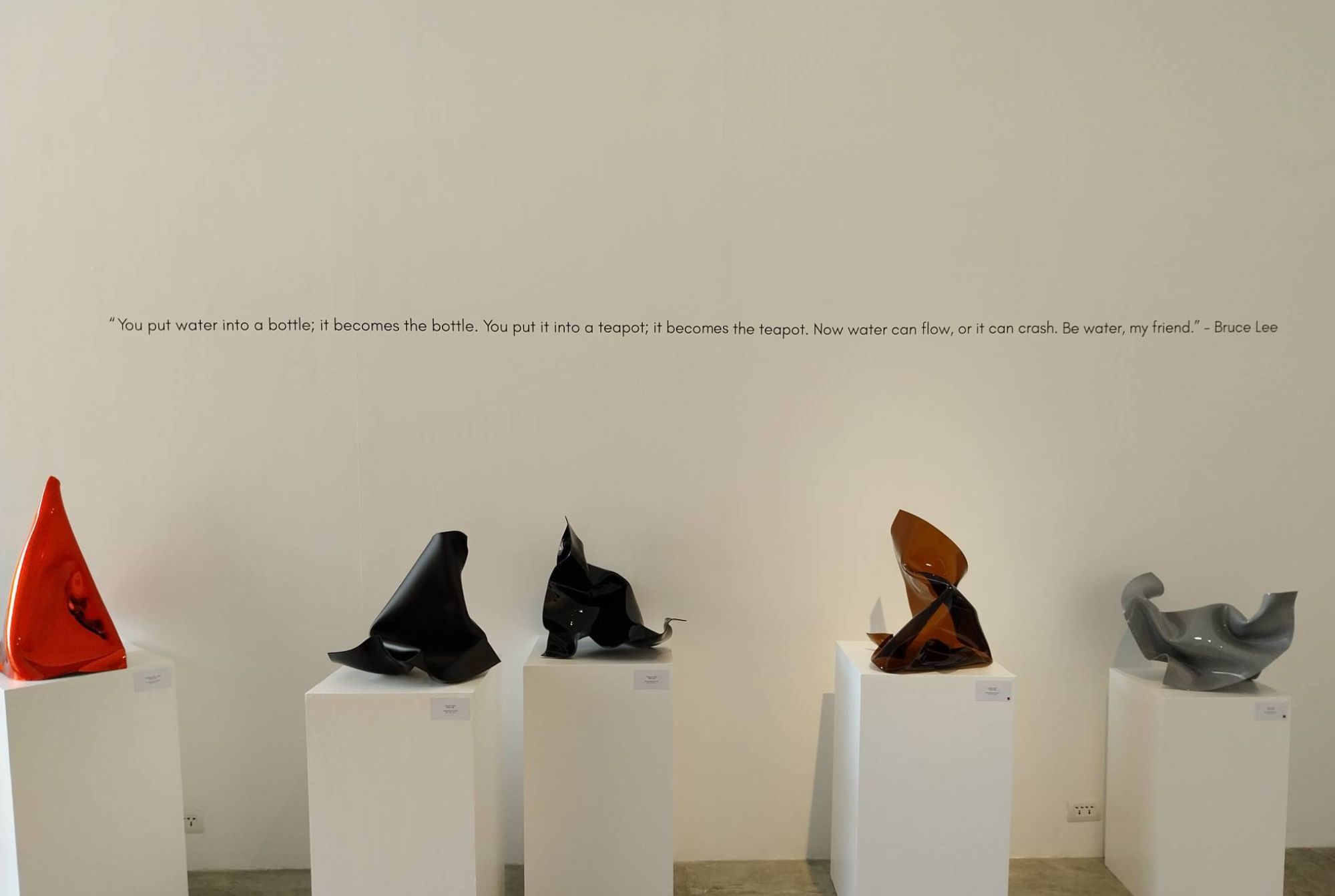 Multiple sculptures for "Be Water" in front of a Bruce Lee quote. Photo by Elle Yap.