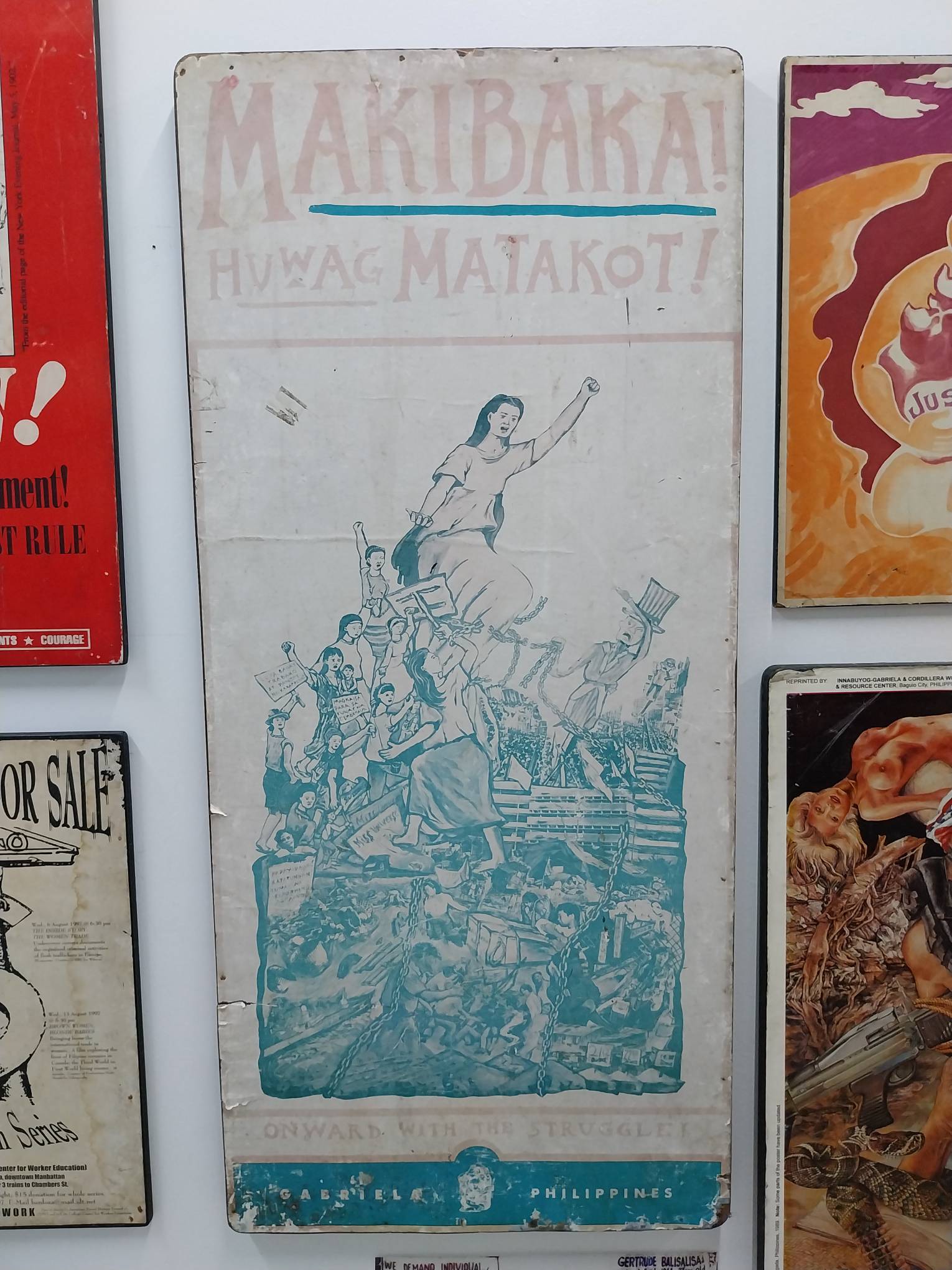 An old poster of a woman with raised fists leading a protest, with "Makibaka, Huwag Matakot!" written in large letters. Photo by Elle Yap.