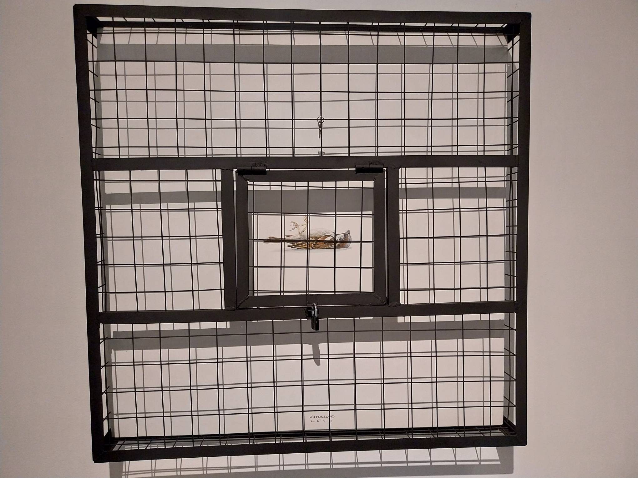 Painting of a dead bird behind a cage. Photo by Elle Yap.