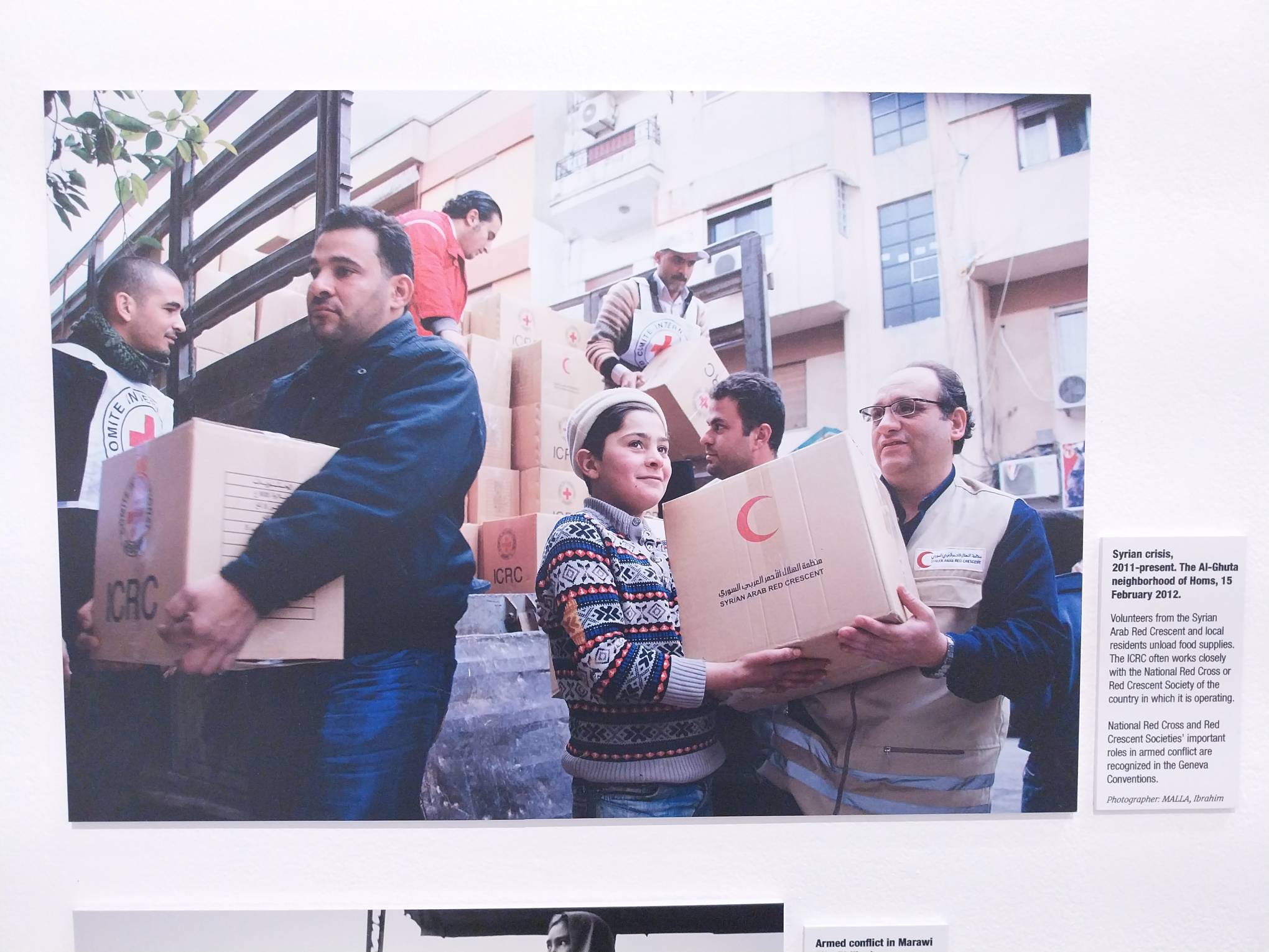 Image of people unloading food rations as shown in “75 Years of the Geneva Conventions." Photo by Elle Yap.
