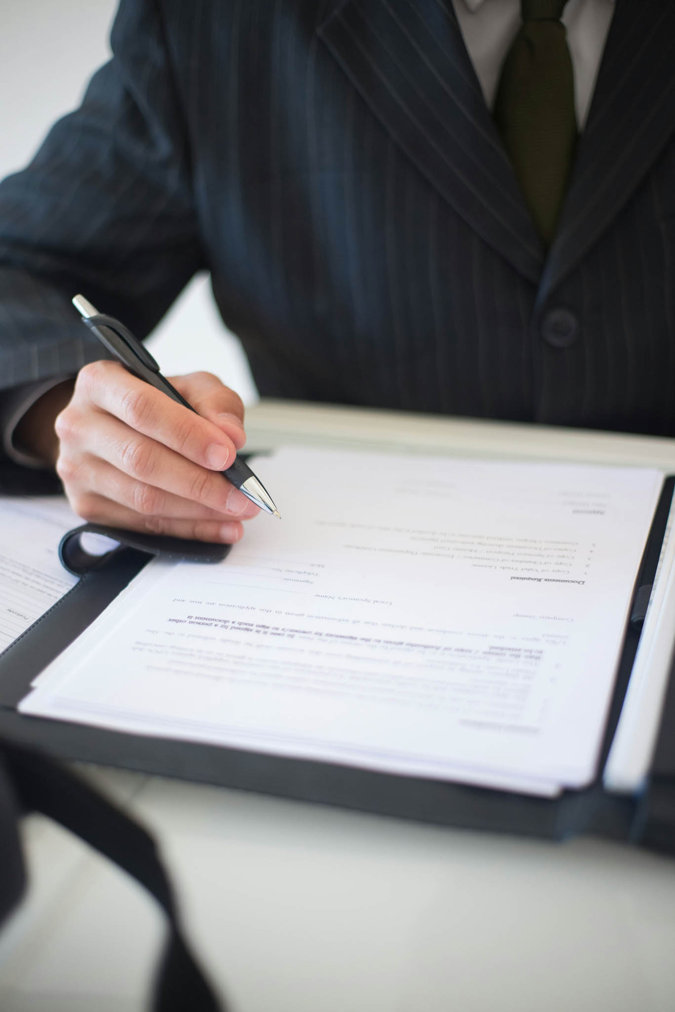 Closeup of a person holding a pen and about to sign a contract.