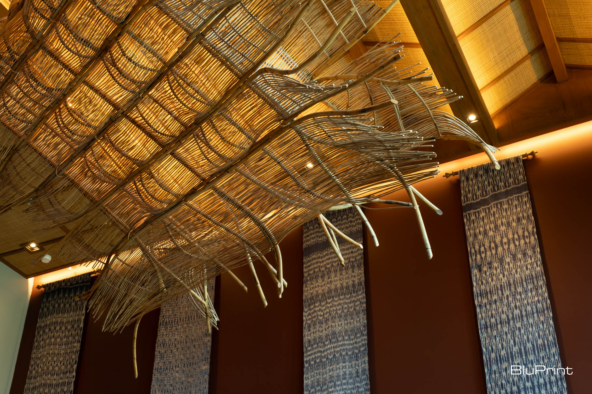 Closeup shot of a pendant lamp hanging from the ceiling and fabrics adorning the wall.