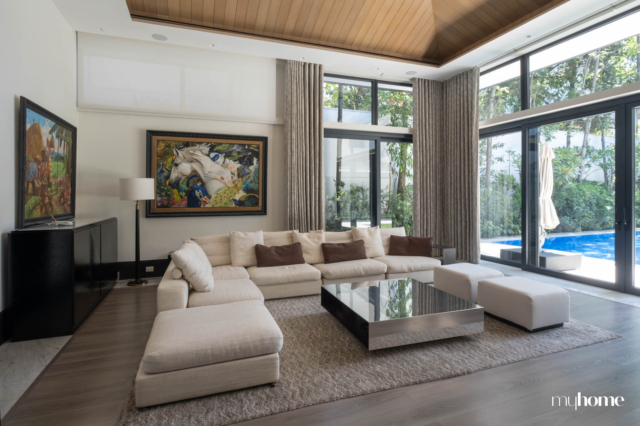 A living area with a light gray couch situated near huge glass windows.