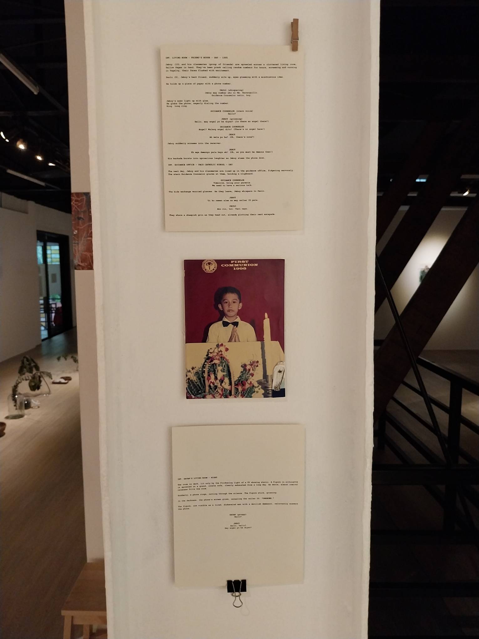 Two pages of a script about Satan with a graduation photo in between. Photo by Elle Yap.