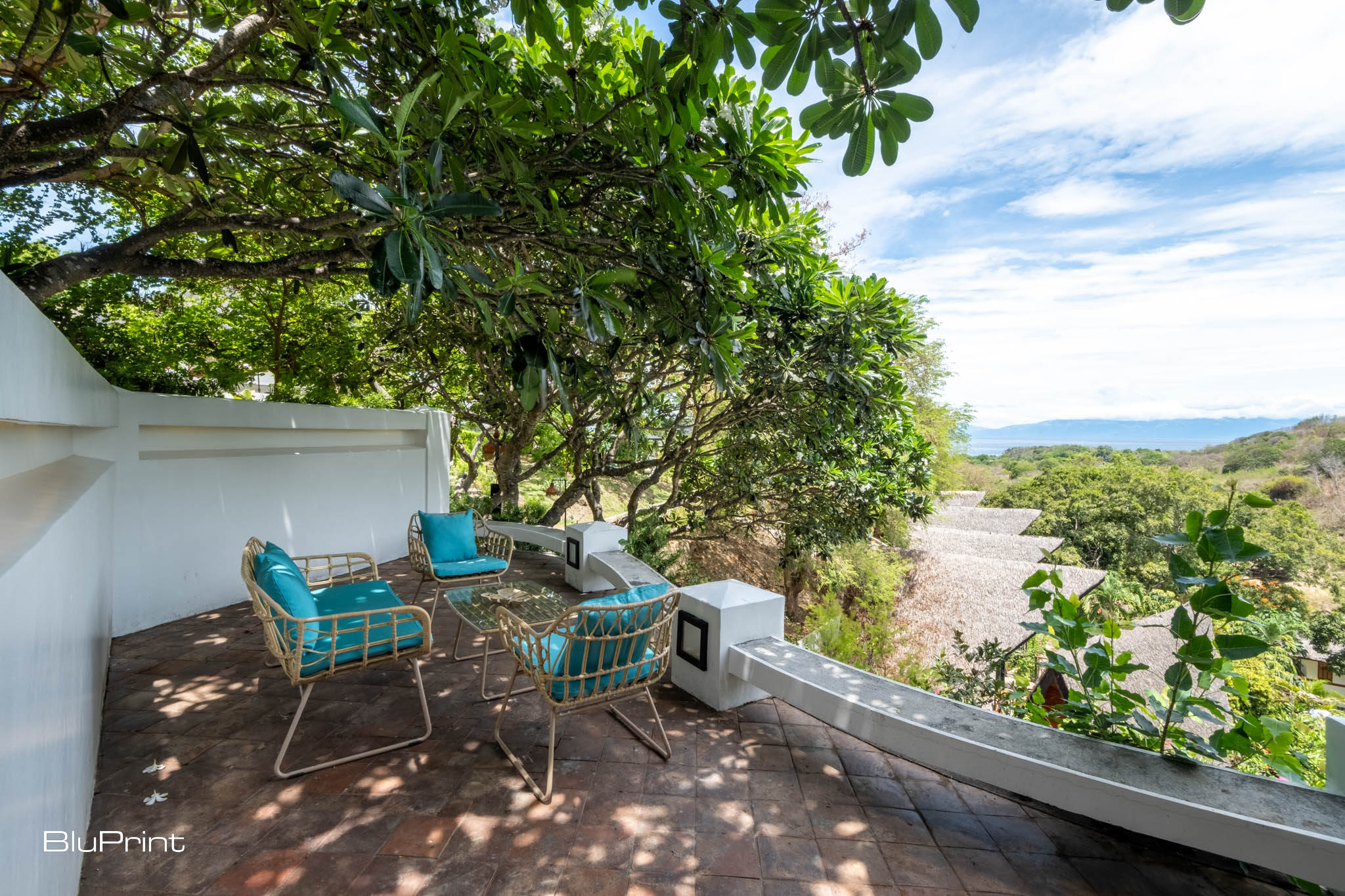 A spacious outdoor area with rattan chairs and turquoise cushions at Nawa Wellness resort, designed by Tania Fricke Lichauco.