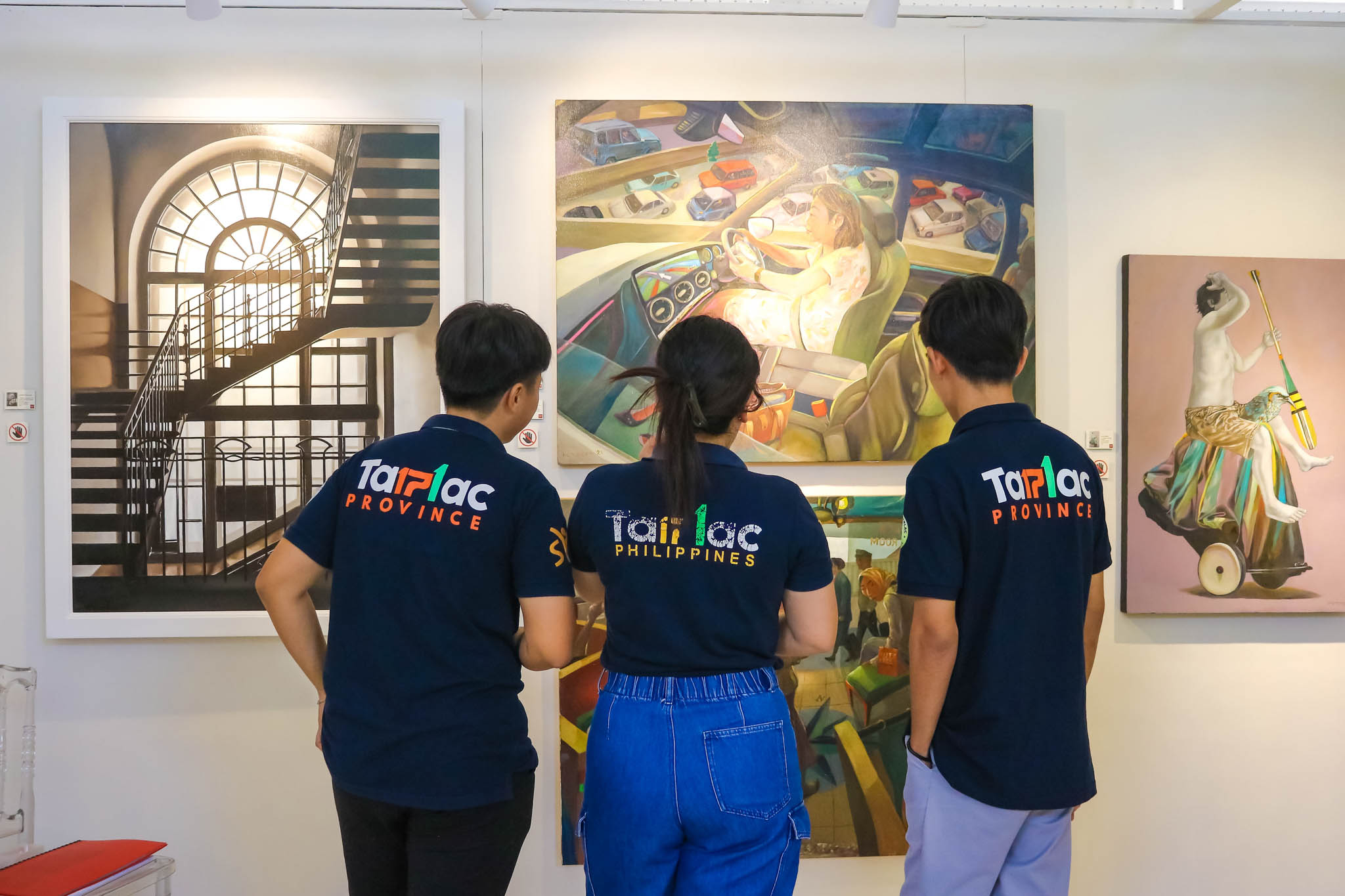 Three people inspecting a painting.