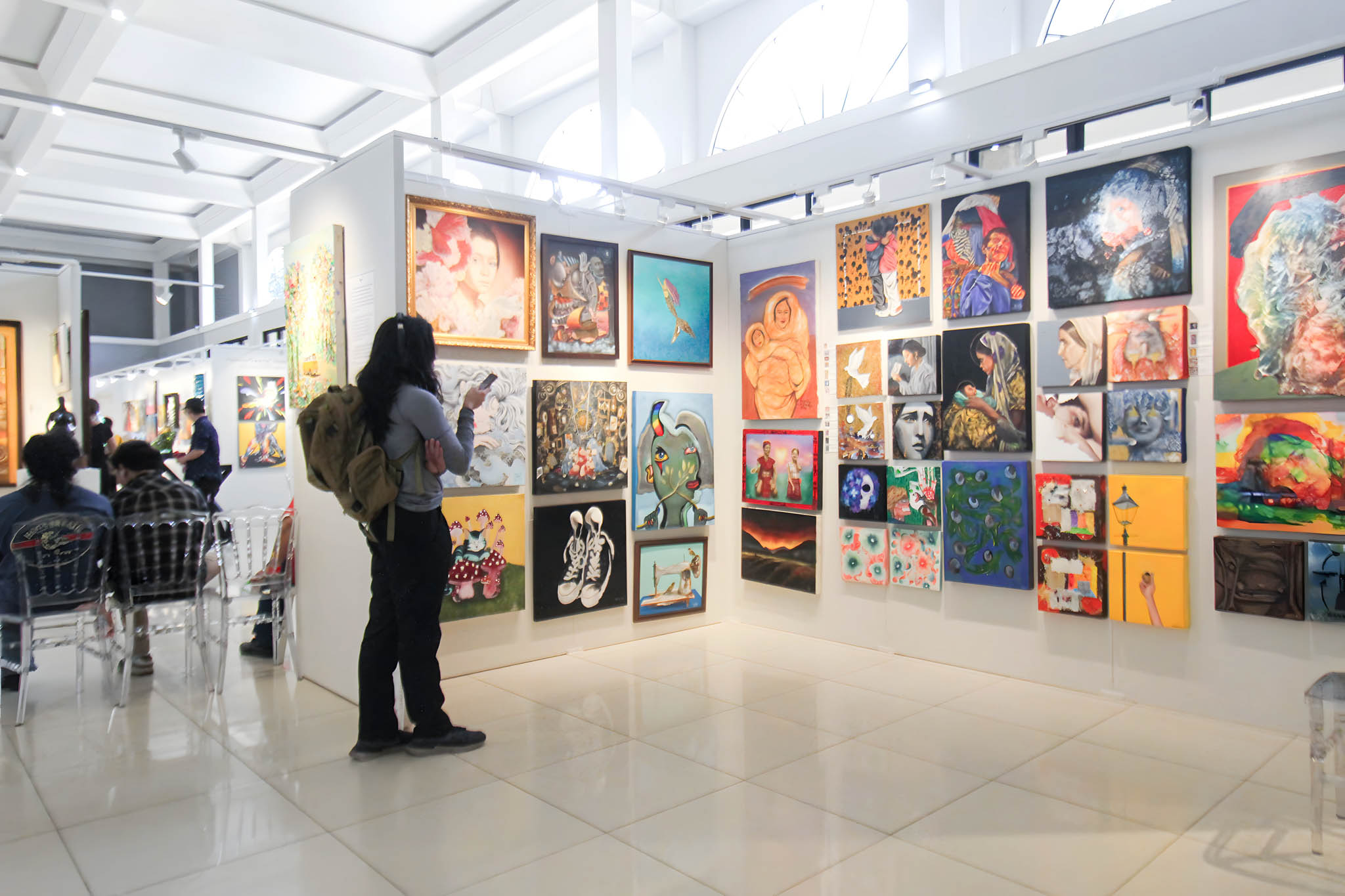 Person looking through a large quantity of paintings at Luzon Art Fair.
