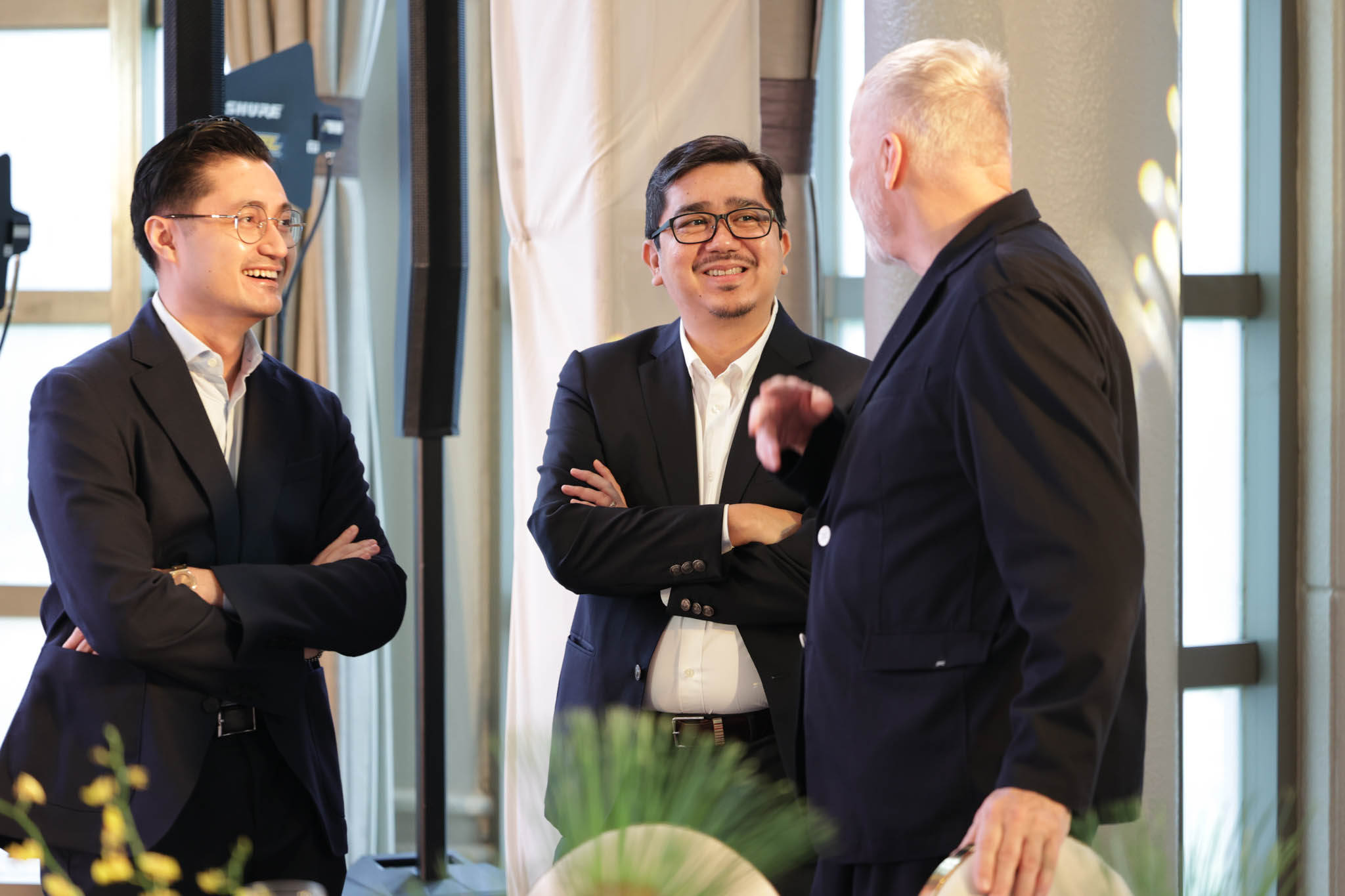Three men standing and discussing at a hotel event venue.