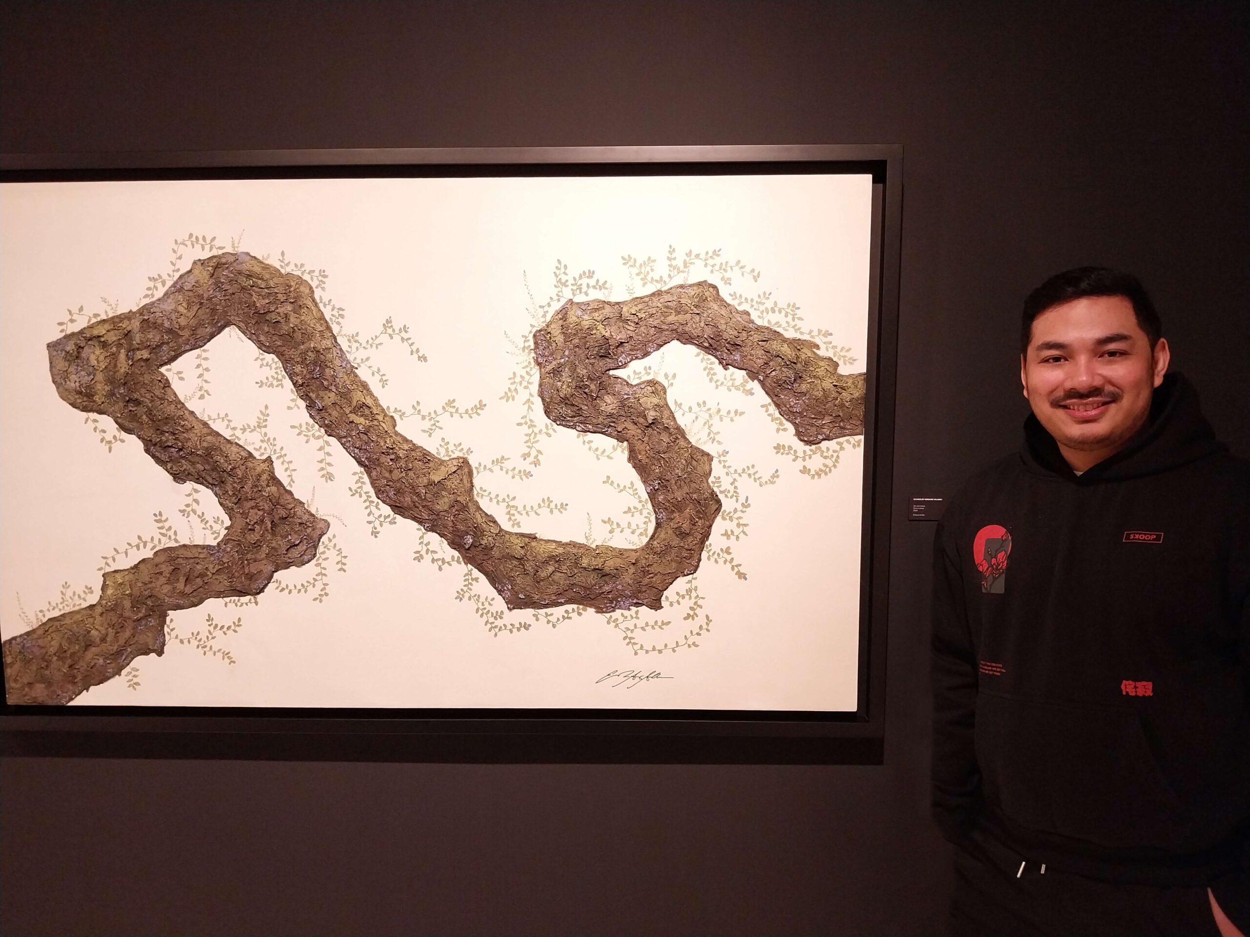 Erikson Arcilla in front of one of his paintings for "Echoes of Verdure."