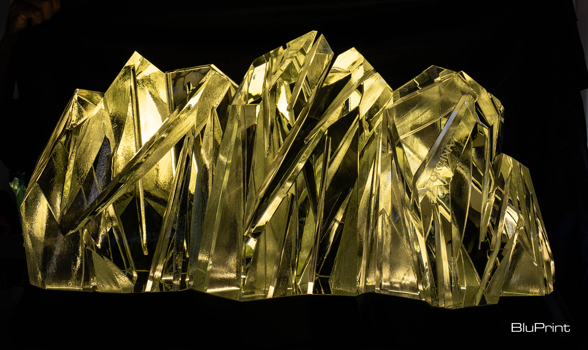 A yellow glass sculpture by Ramon Orlina resembling a mountain range.