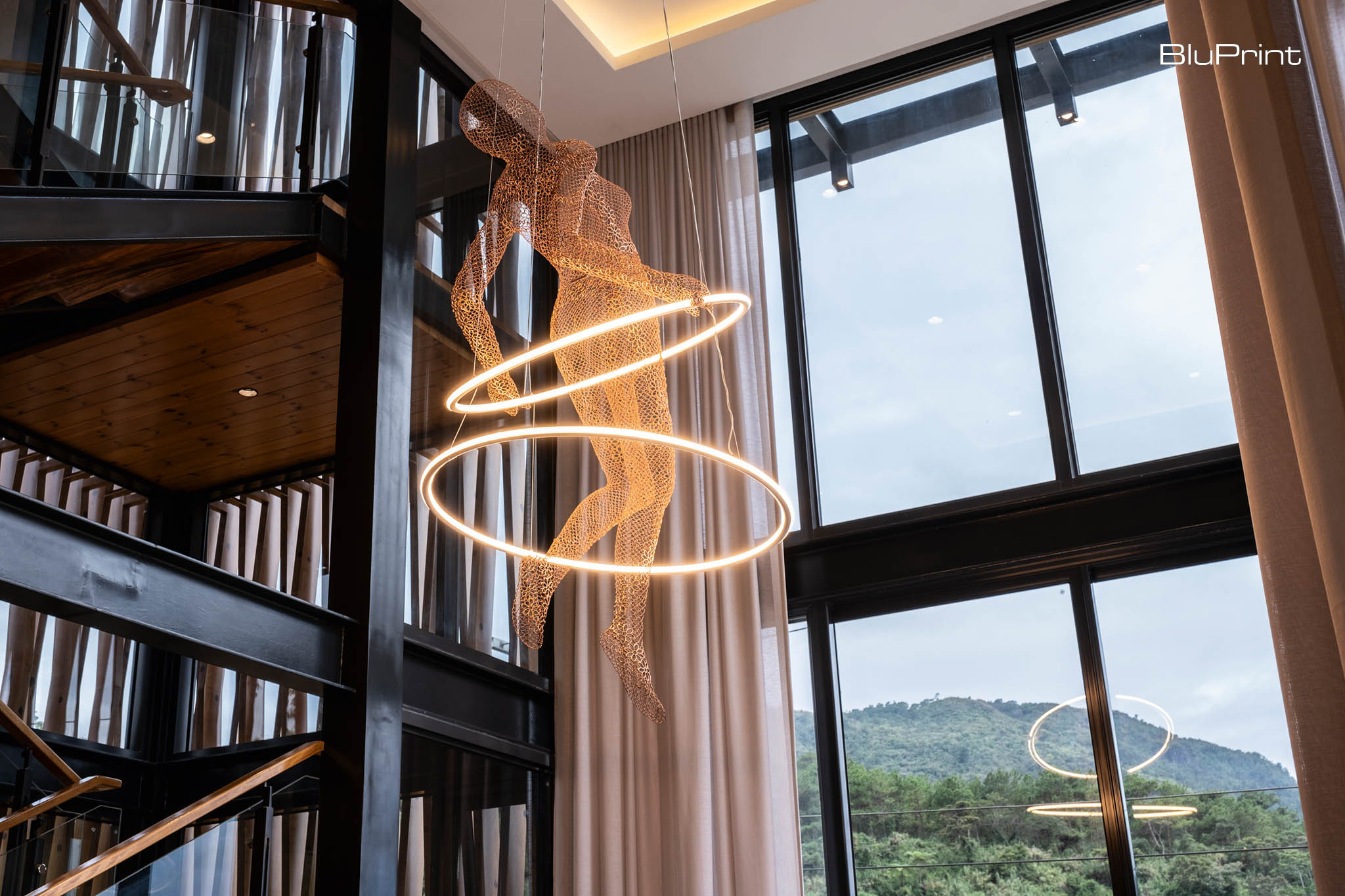 A Serene Mountain Retreat by Fitnesscape Creative Studio Inc. The sculptural light serves as both a striking design statement and a functional feature, casting soft ambient light and enhancing the room's aesthetic with its artistic form.