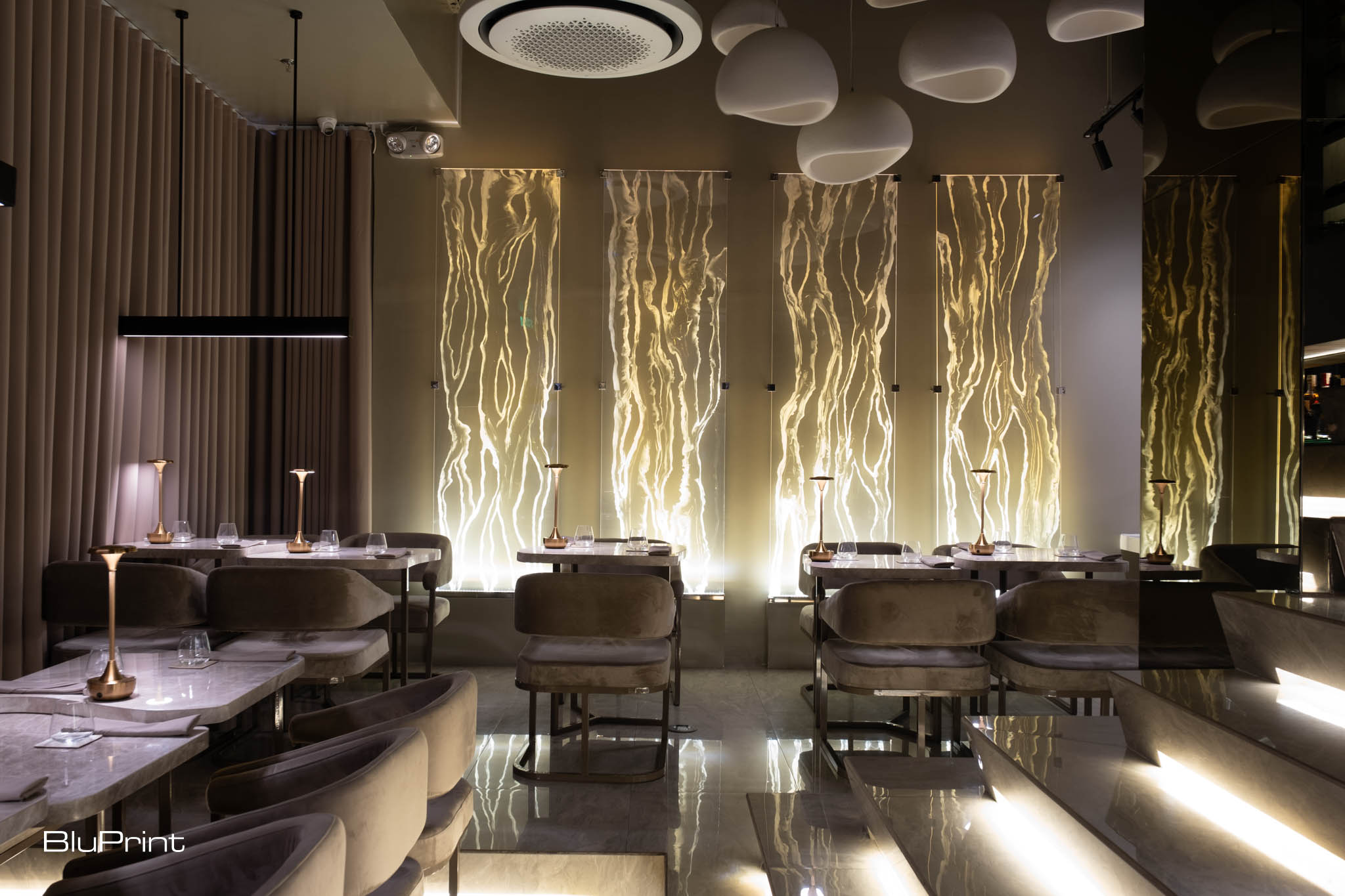 Interiors of Taupe restaurant showing decorative resin panels, dining tables, and chairs.